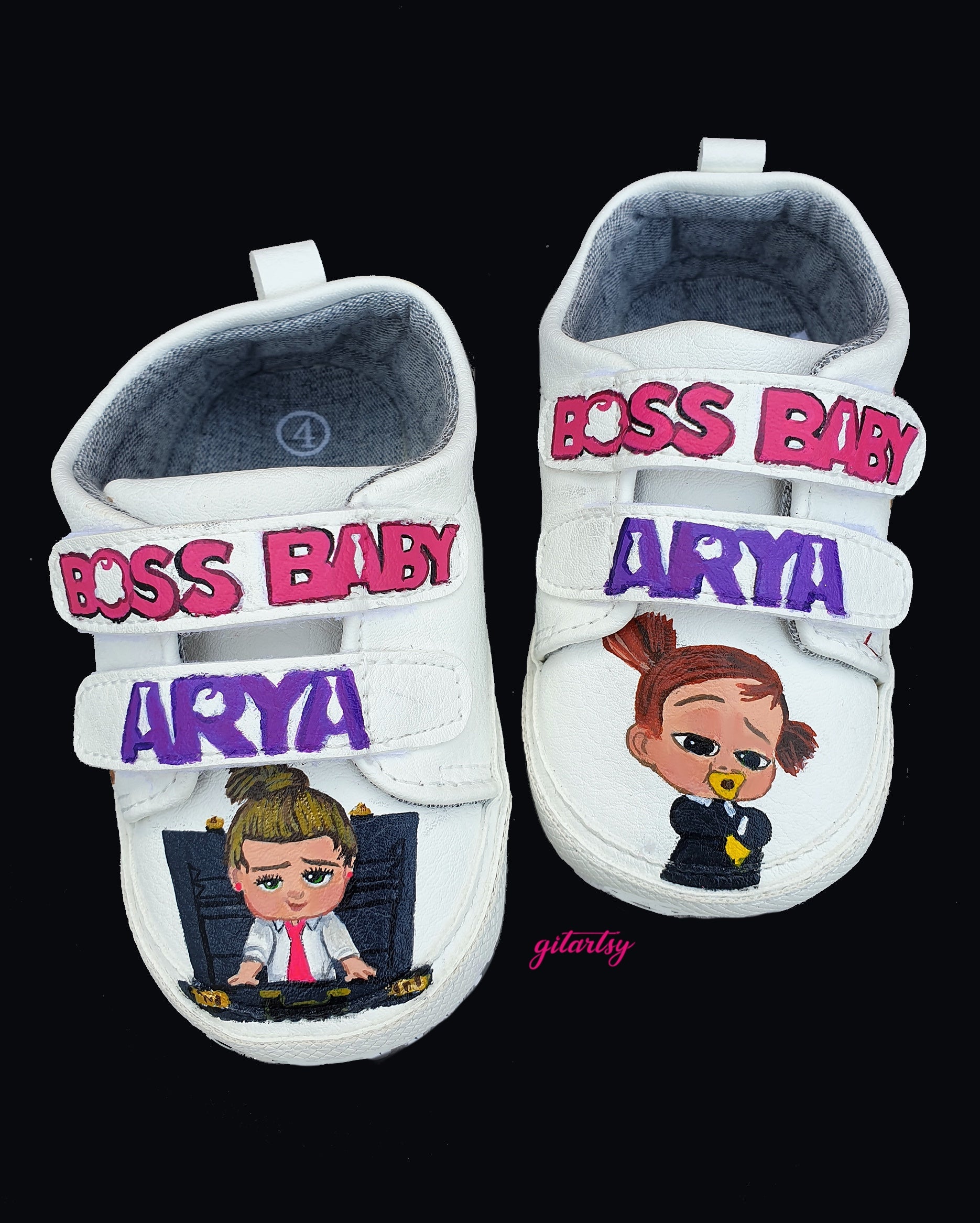 Custom hand-painted baby sneakers featuring Boss Baby theme. The shoes are white with colorful baby illustrations like pacifiers, bottles, cookies, and the name "Arya" painted in bold letters. Boss Baby characters are painted on the front, and birthdate details like "18/10/2020" and "October" are added on the back. Each pair is personalized, vibrant, and made for babies or toddlers as keepsakes or gifts.