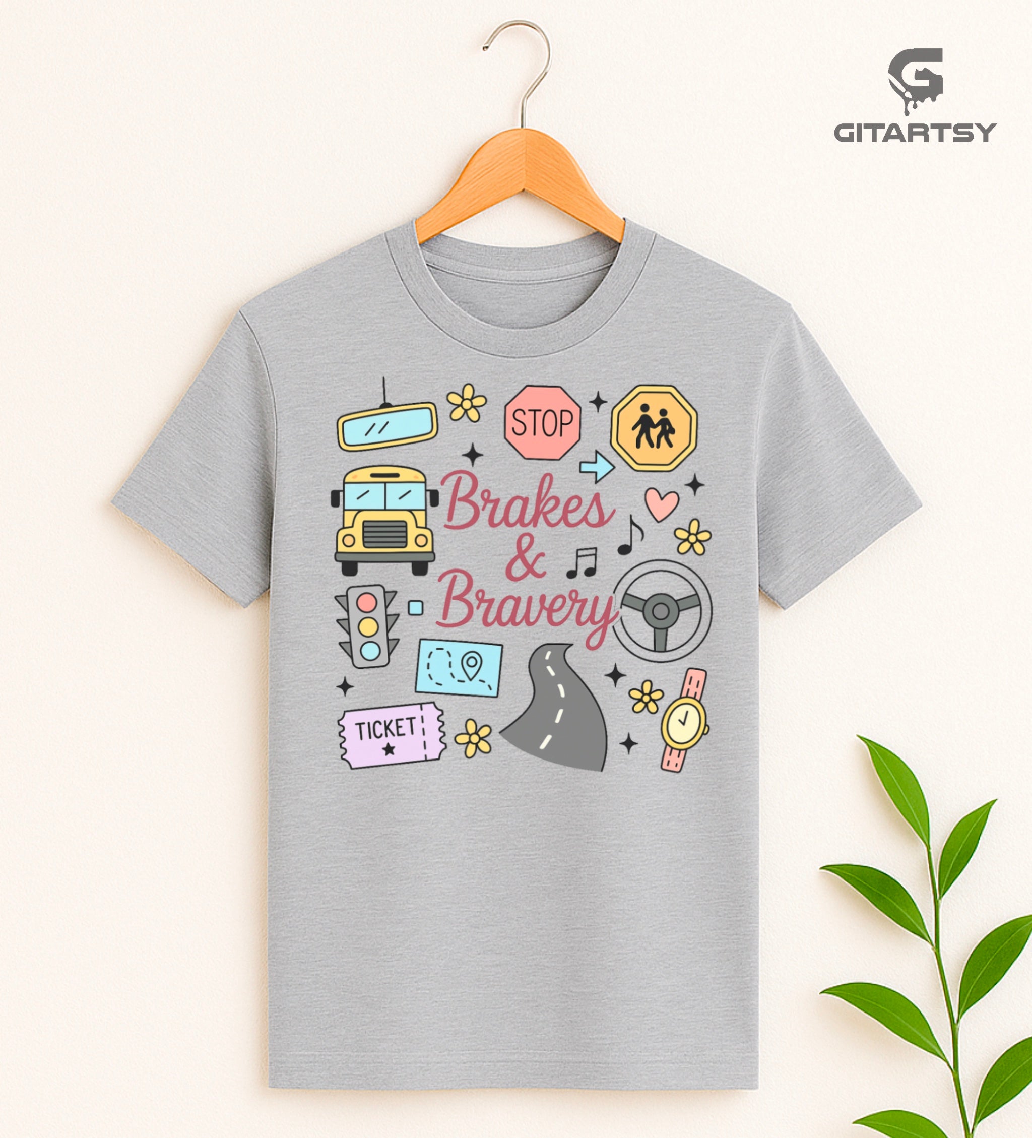 Pastel T-shirt with “Brakes & Bravery” design featuring illustrated school bus, road signs, steering wheel, and driving elements – ideal gift for bus drivers and transport staff