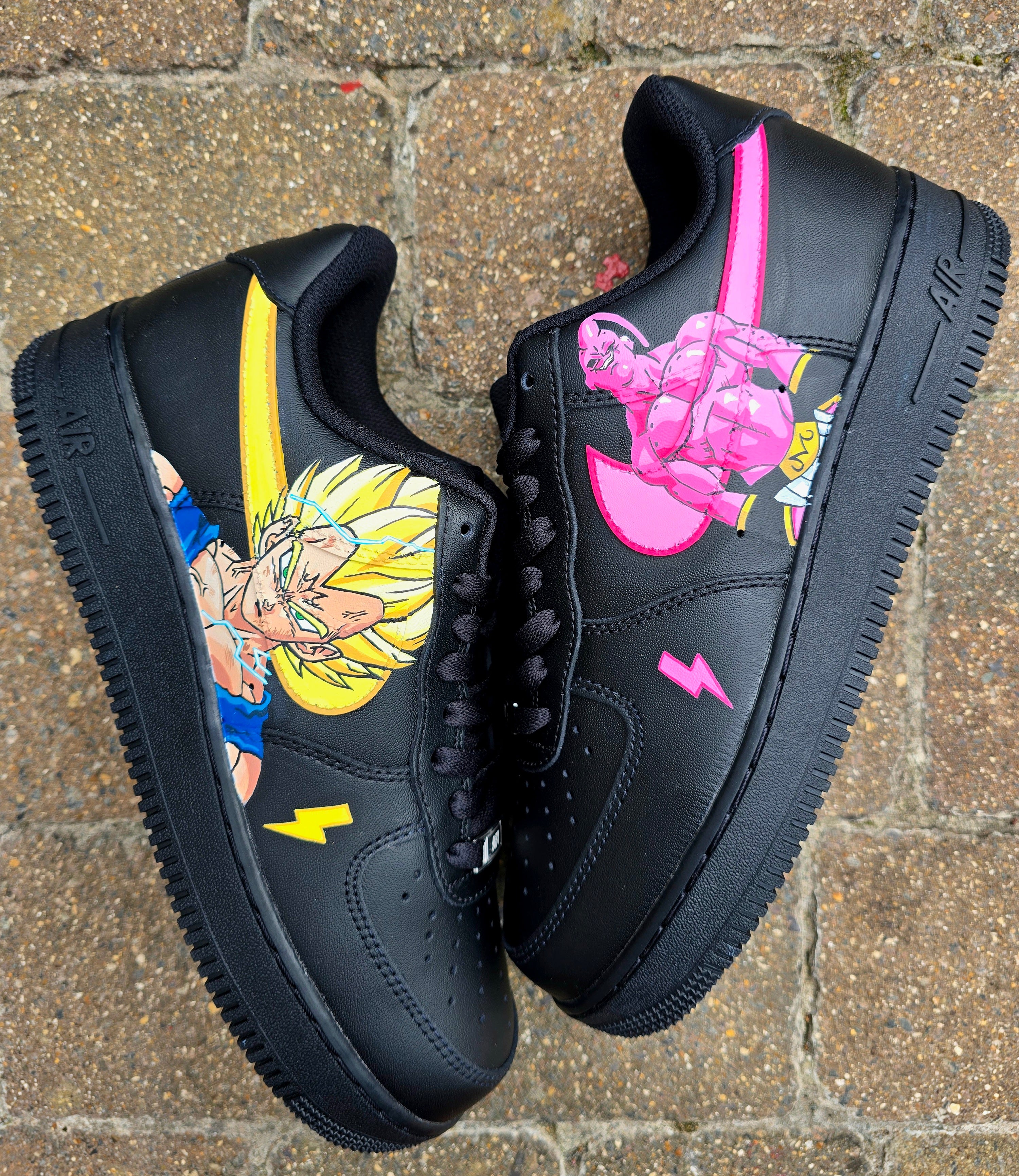 Custom Dragon Ball Z Nike Air Force 1 sneakers featuring hand-painted anime artwork of Majin Buu and Super Saiyan Goku. Black leather base with pink and yellow accents, lightning bolt details, and high-quality, waterproof custom paint job.