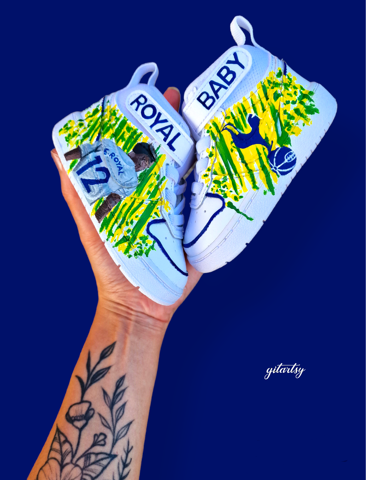 Custom hand-painted baby Adidas sneakers inspired by Brazilian footballer Emerson Royal. Features toddler-sized high-top shoes with illustrations of Emerson in Spurs and Brazil kits, Brazil flag background, colorful 3-stripes, and "Emerson Royal" detailing on the heel. Designed for toddlers, crafted with non-toxic paint, and finished with vibrant detailing by Gitartsy.