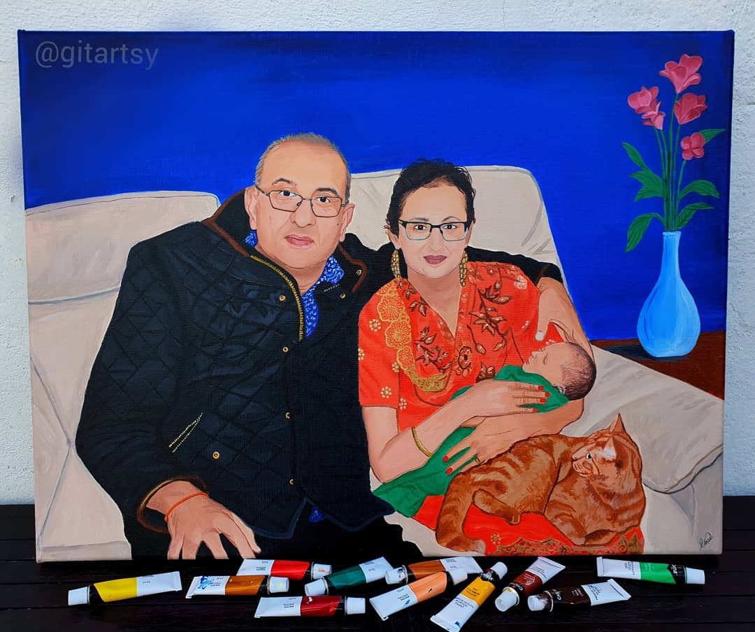 Hand‑painted realistic acrylic portrait on canvas depicting a smiling couple seated on a cream sofa, the woman in a red patterned dress cradling their sleeping newborn wrapped in a green blanket while an orange tabby cat lounges beside her; vivid royal‑blue background with a minimalist side table and blue vase of pink flowers, rendered in lifelike detail and rich colour.