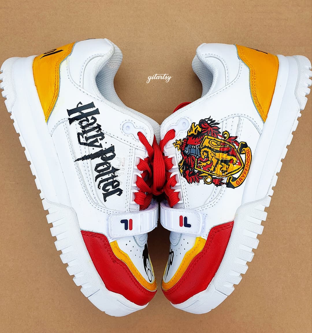 Custom hand-painted Fila sneakers featuring detailed Harry Potter-themed artwork including the Gryffindor crest, HP initials, lightning bolt, Harry’s iconic glasses, and vibrant house colors. Designed for fans who want wearable art with a magical touch. Made by Gitartsy.