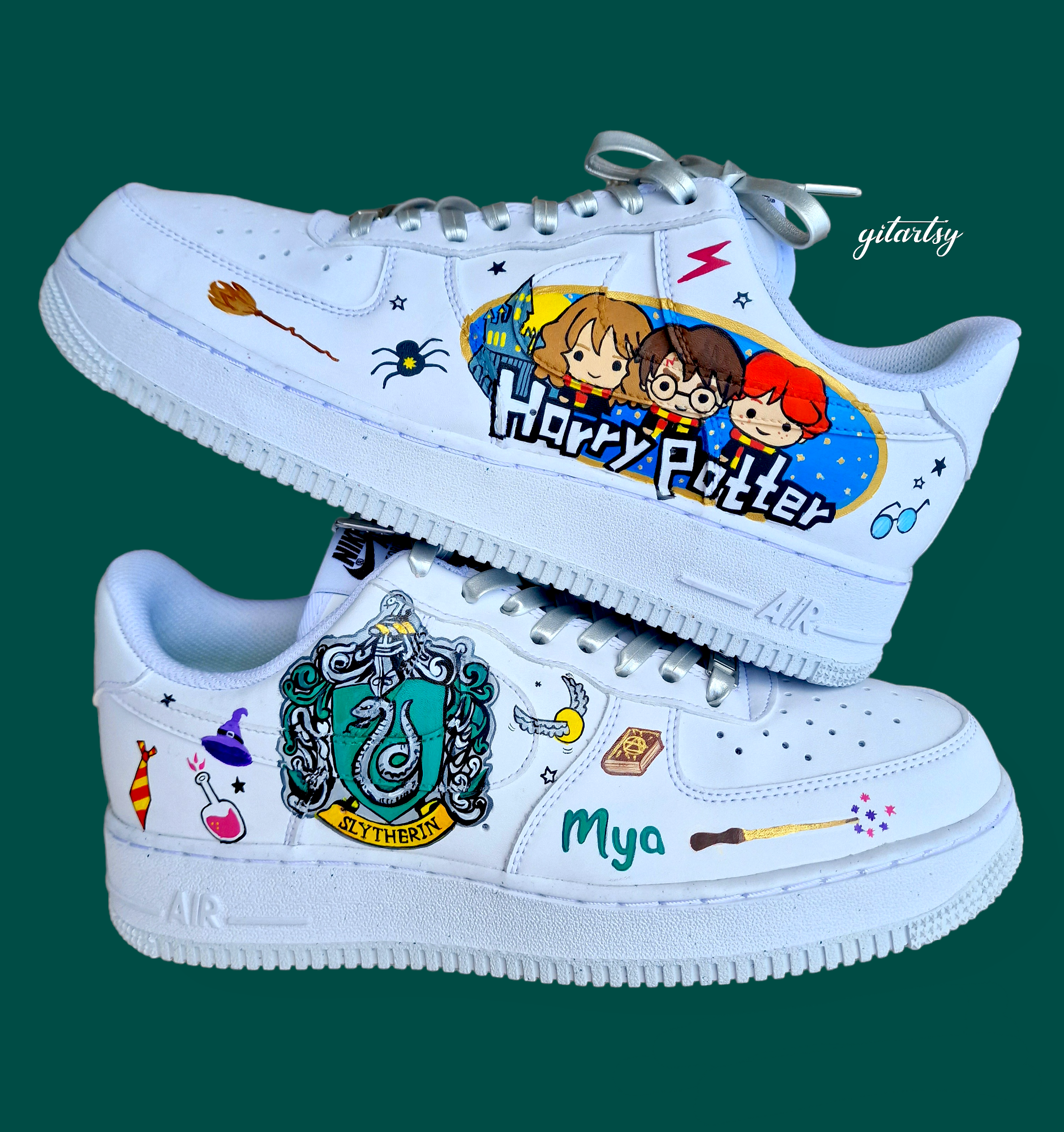 Custom hand-painted Nike Air Force 1 sneakers designed with a Harry Potter theme featuring detailed artwork of the Slytherin house crest, magic potions, broomsticks, spell books, a flying key, and cute chibi-style illustrations of Harry, Hermione, and Ron. The white leather base is transformed into wearable art, personalised with a name ("Mya") and wizarding elements, all sealed for durability and vibrancy.