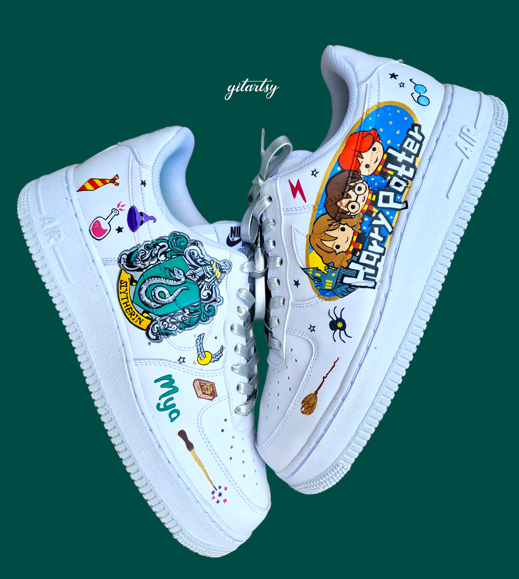 Custom hand-painted Nike Air Force 1 sneakers designed with a Harry Potter theme featuring detailed artwork of the Slytherin house crest, magic potions, broomsticks, spell books, a flying key, and cute chibi-style illustrations of Harry, Hermione, and Ron. The white leather base is transformed into wearable art, personalised with a name ("Mya") and wizarding elements, all sealed for durability and vibrancy.