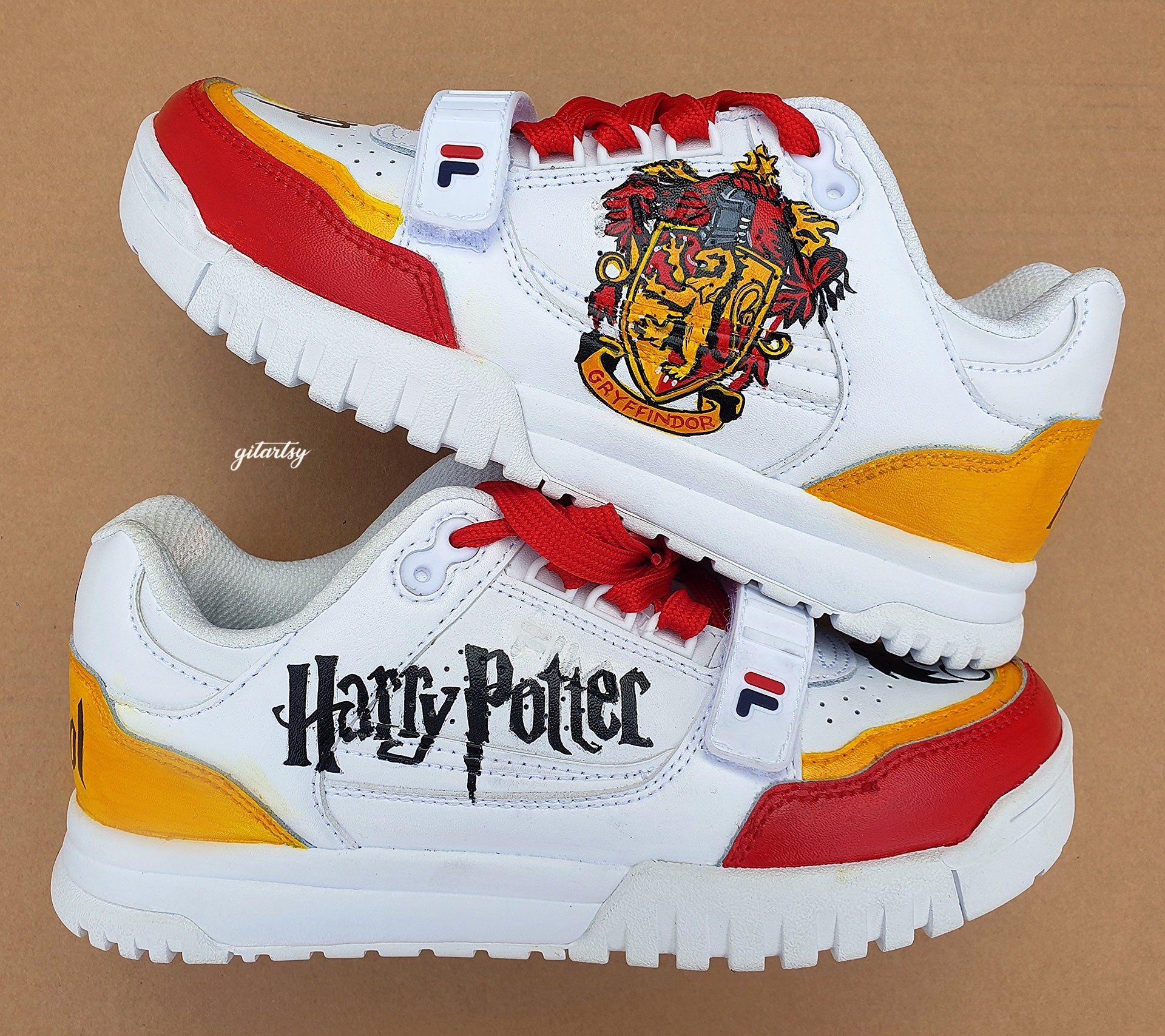 Custom hand-painted Fila sneakers featuring detailed Harry Potter-themed artwork including the Gryffindor crest, HP initials, lightning bolt, Harry’s iconic glasses, and vibrant house colors. Designed for fans who want wearable art with a magical touch. Made by Gitartsy.