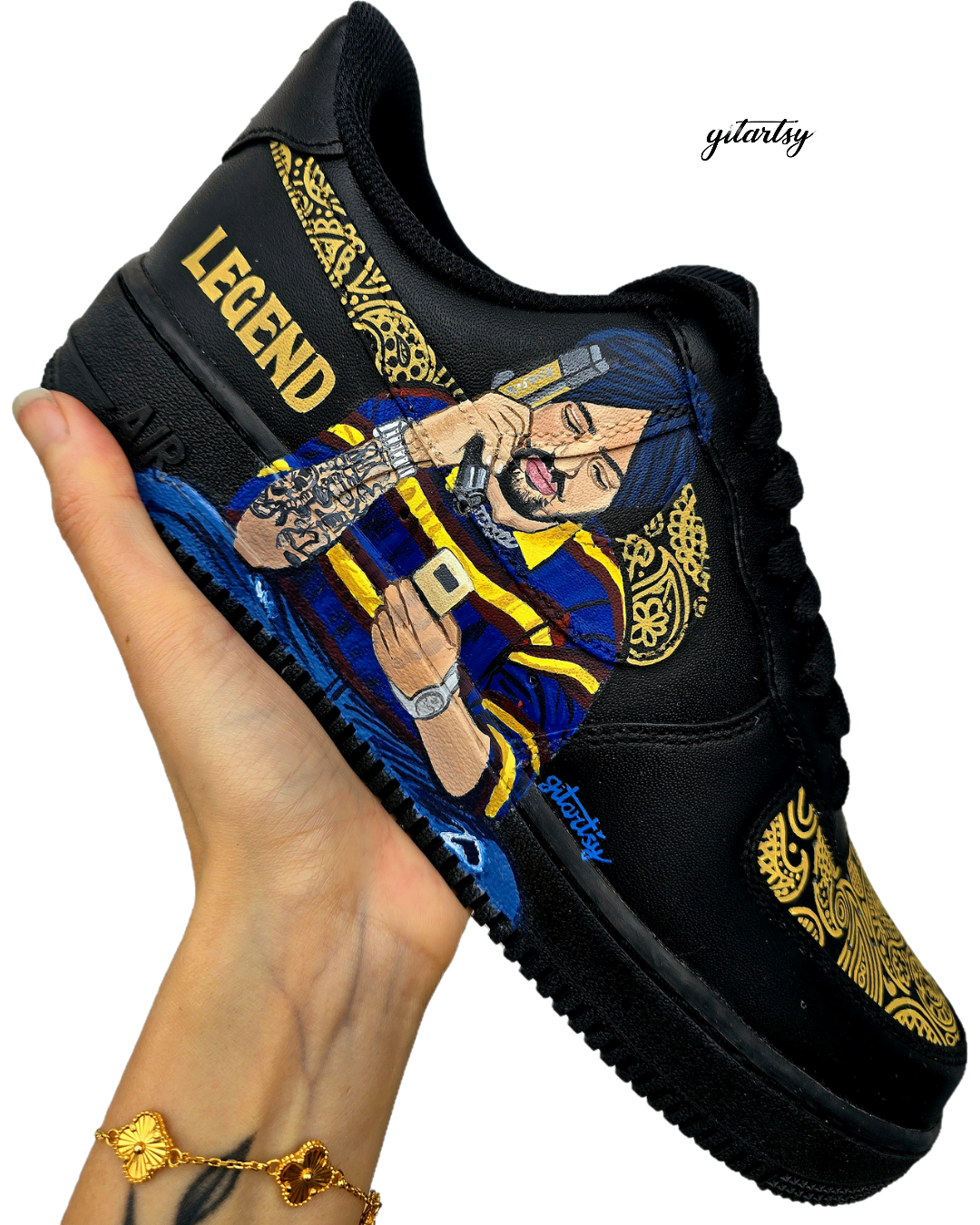 Custom black Nike Air Force 1 sneakers featuring detailed hand-painted artwork including a realistic portrait of Sidhu Moosewala on one side, and a lifelike hand wearing a silver kara and gold jewelry on the other, surrounded by intricate golden Punjabi patterns with bold text that reads “LEGEND” and “SMW”, designed by Gitartsy.