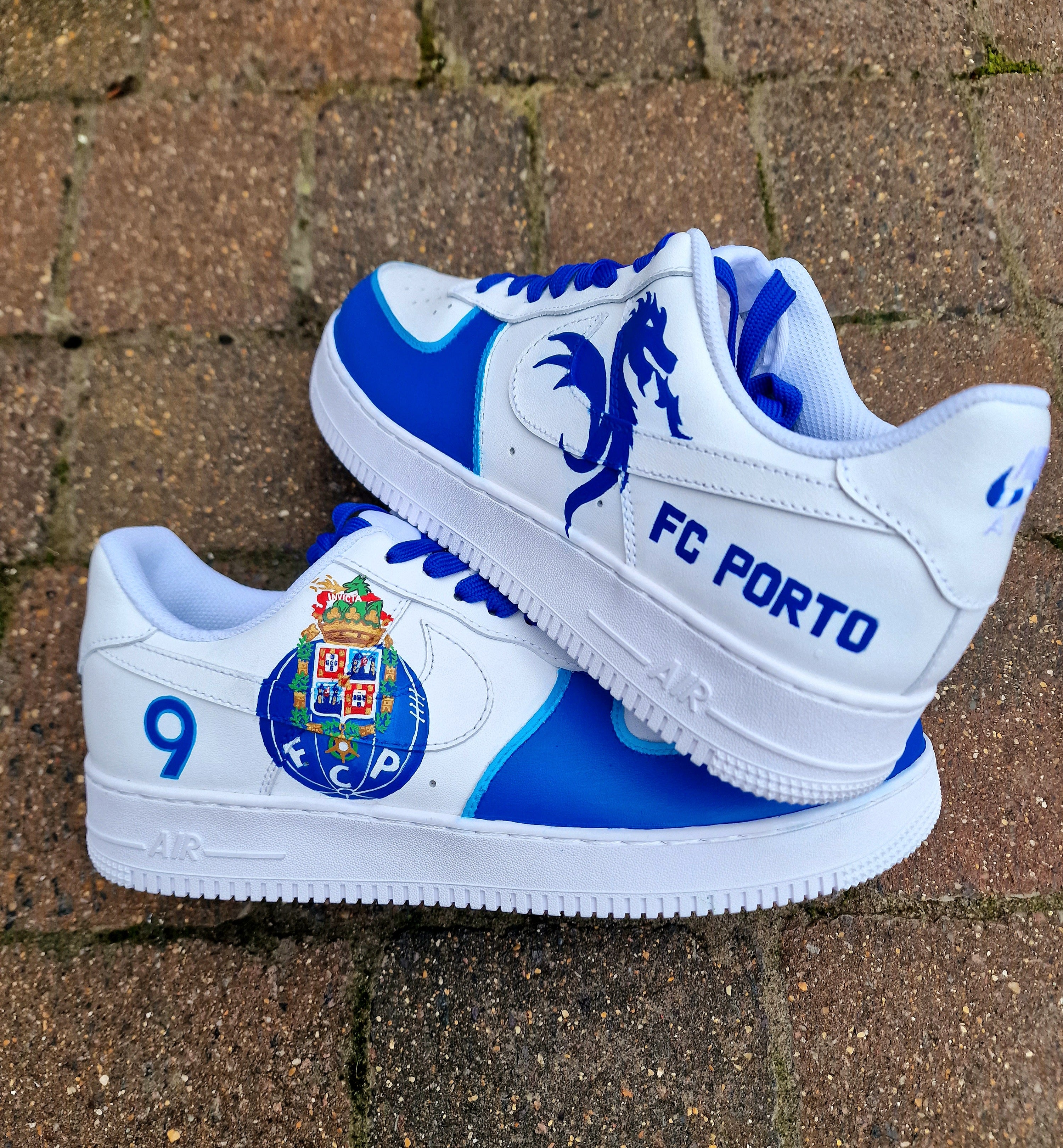 Custom FC Porto Nike Air Force 1 sneakers designed for football fans, featuring hand-painted artwork with the official club crest, blue and white color scheme, dragon mascot, and player number detailing. These one-of-a-kind shoes are crafted using authentic Nike AF1s and painted with weather-resistant leather paints. Perfect for sports lovers and collectors, combining comfort with team spirit.