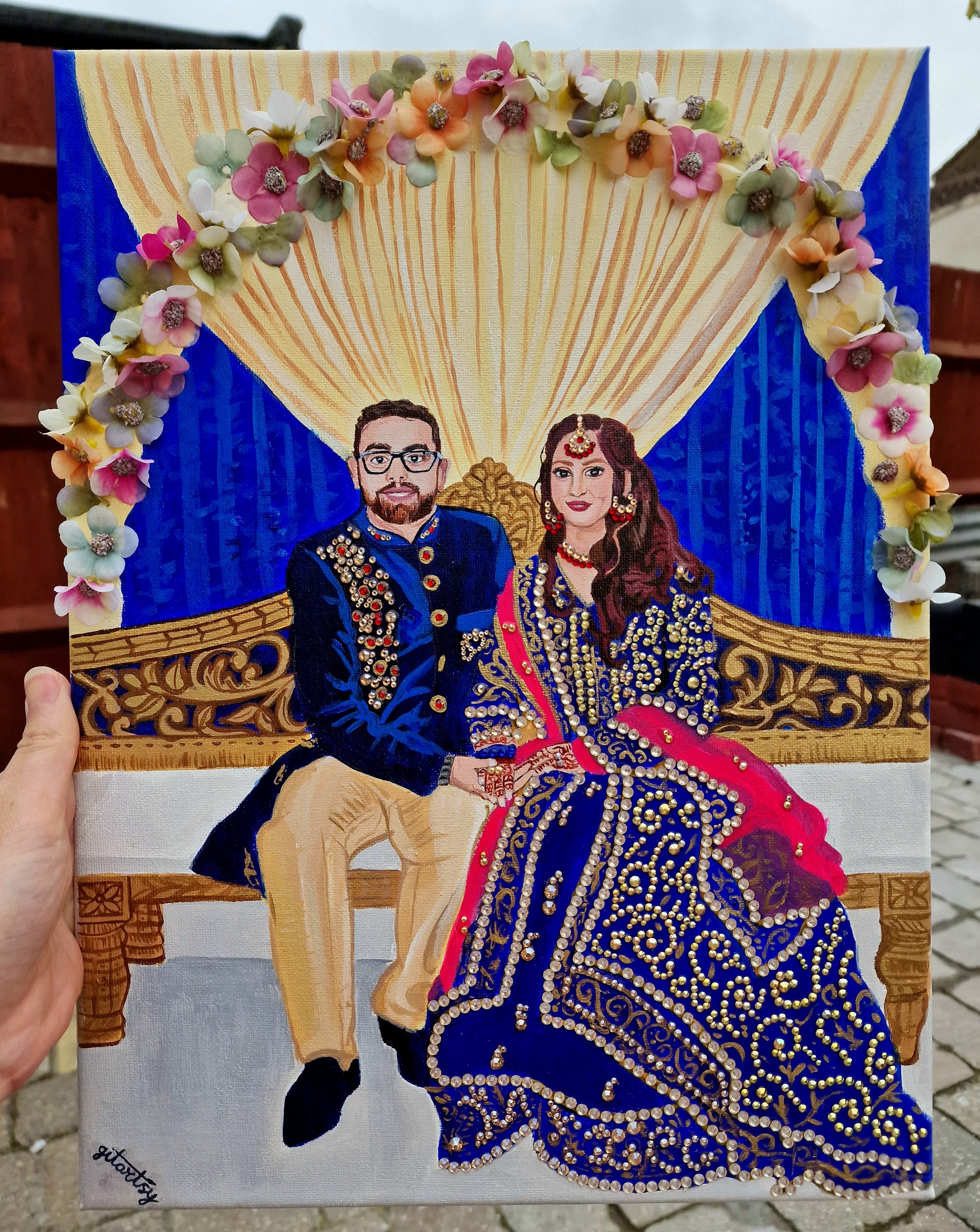 A luxurious hand-painted wedding portrait canvas of a bride and groom in traditional attire, embellished with 3D floral garlands, shimmering gold rhinestones, and detailed fabric textures. A vibrant and elegant custom artwork perfect for wedding gifts or keepsakes.
