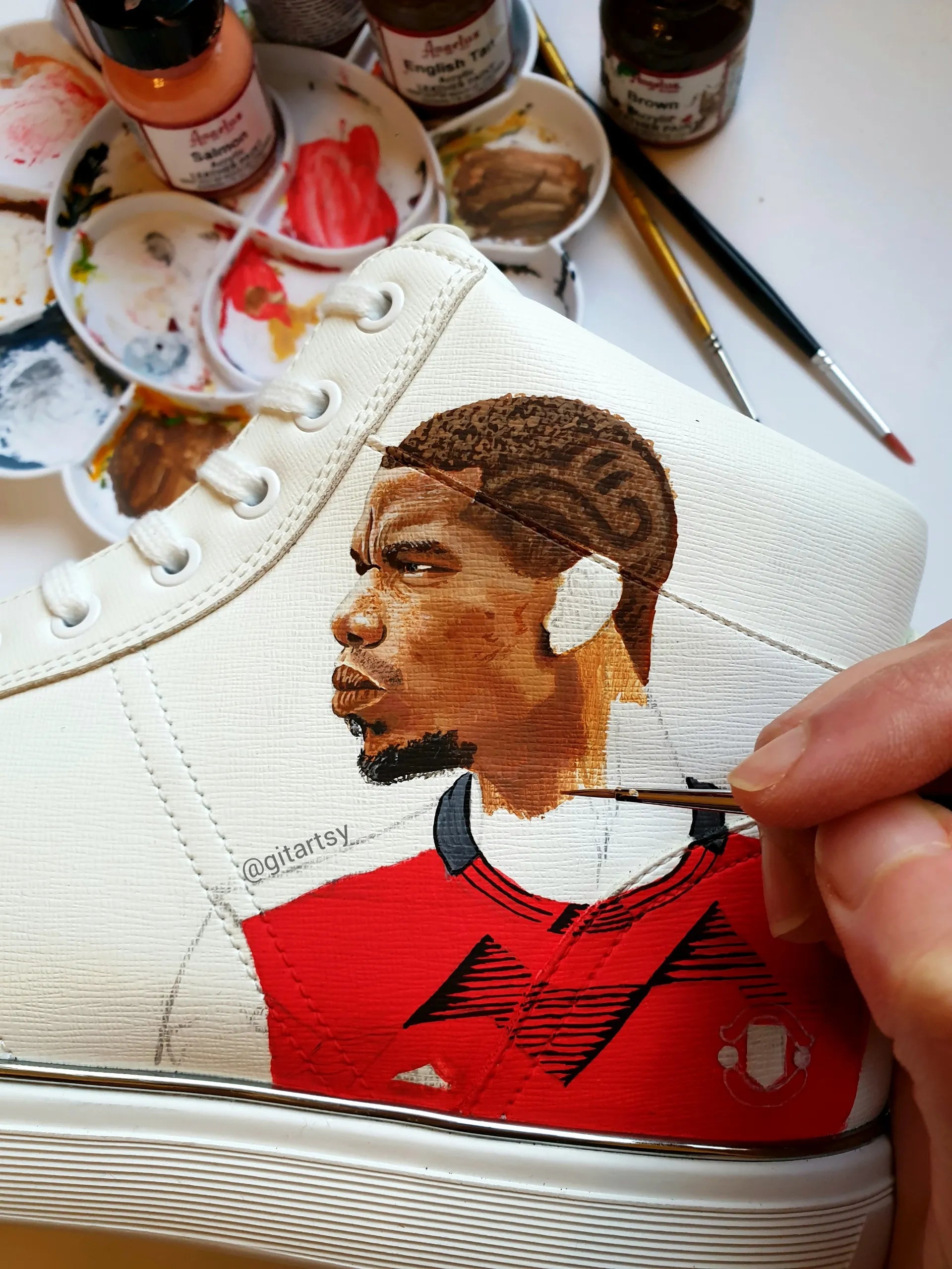 A realistic portrait of Paul Pogba and Manchester United logo hand painted on high-top white sneakers KICKS