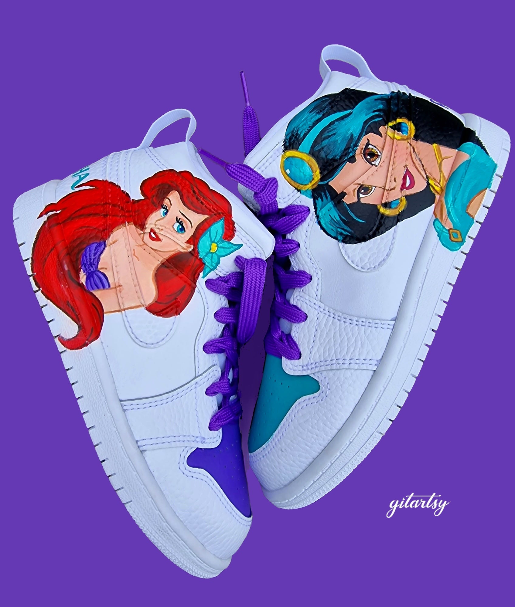 A pair of white Nike toddler sneakers hand-painted with detailed portraits of Disney princesses Jasmine and Ariel. Jasmine is painted in her turquoise outfit with gold accessories, while Ariel is shown with her iconic red hair and purple seashell top. The shoes feature complementary purple and teal accents, vibrant laces, and optional personalised names on the heel in matching colors.