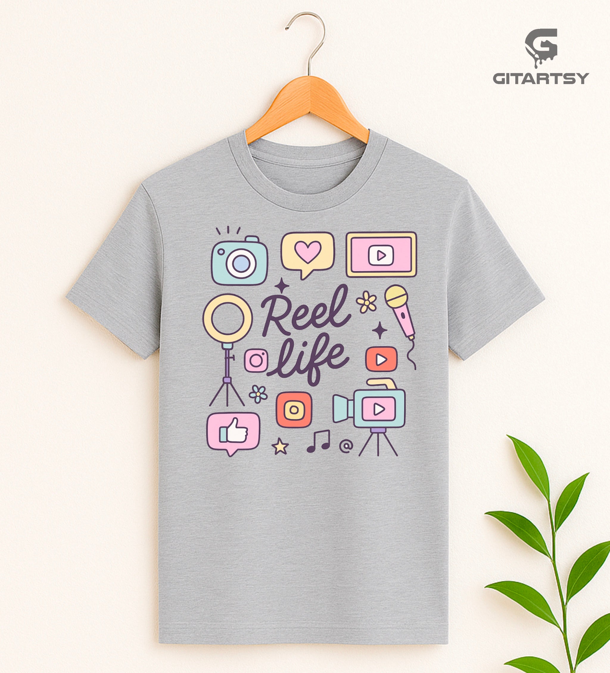Pastel “Reel Life” T-shirt with social media icons, camera, microphone, and content creator doodles – ideal for influencers, vloggers, and content creators