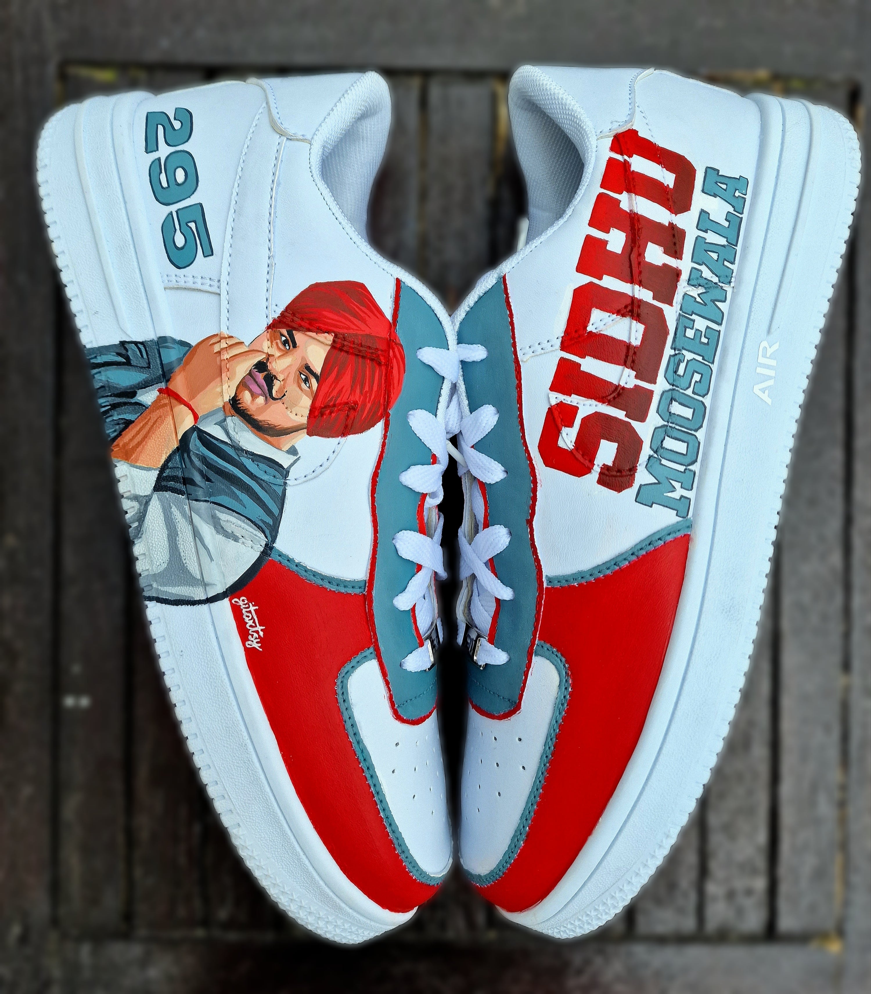 Custom white Nike sneakers hand-painted with a realistic portrait of Punjabi singer Sidhu Moosewala, featuring the number "295" and his name "SIDHU MOOSEWALA" across the sides. The design includes a red, white, and teal color theme, crisp linework, and street-style artistry—perfect for fans and collectors.