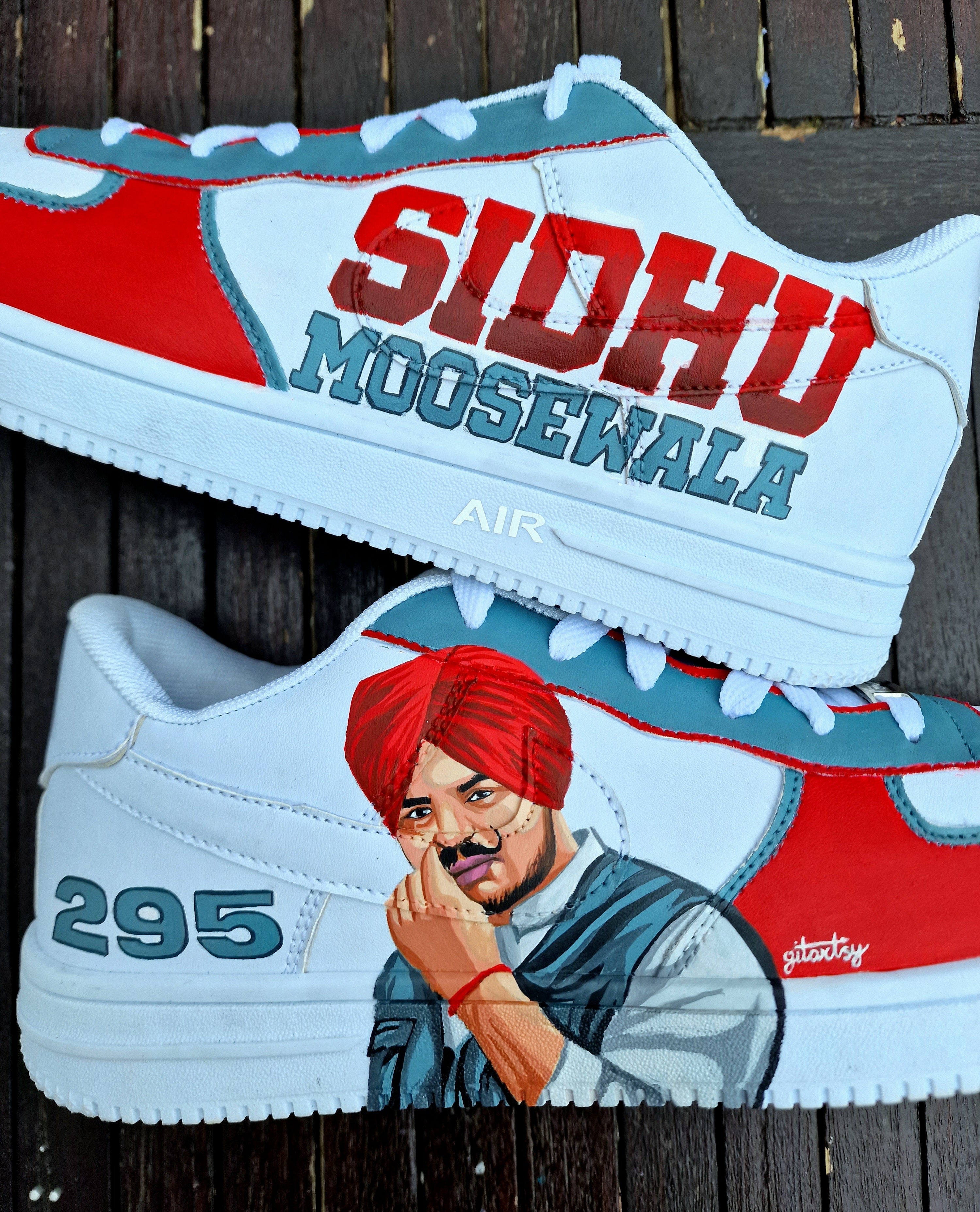 Custom white Nike sneakers hand-painted with a realistic portrait of Punjabi singer Sidhu Moosewala, featuring the number "295" and his name "SIDHU MOOSEWALA" across the sides. The design includes a red, white, and teal color theme, crisp linework, and street-style artistry—perfect for fans and collectors.
