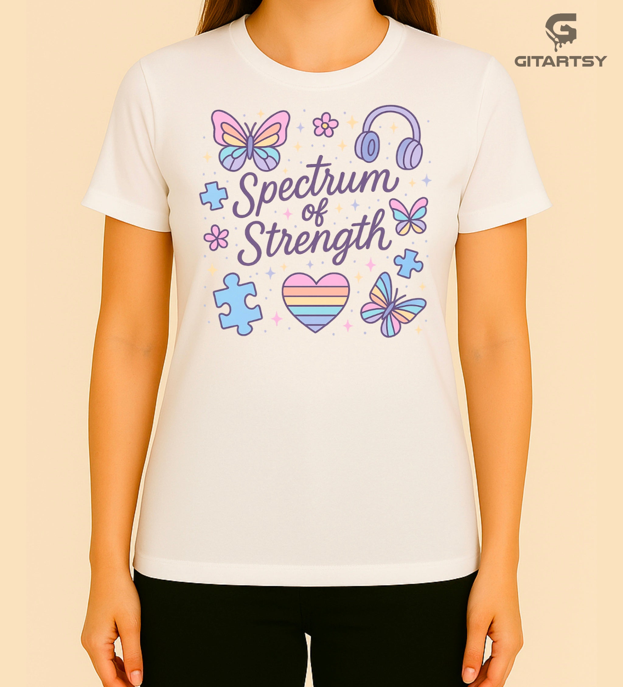 T-shirt with pastel illustrations of butterflies, puzzle pieces, headphones, and the words “Spectrum of Strength”—a positive message celebrating neurodiversity.