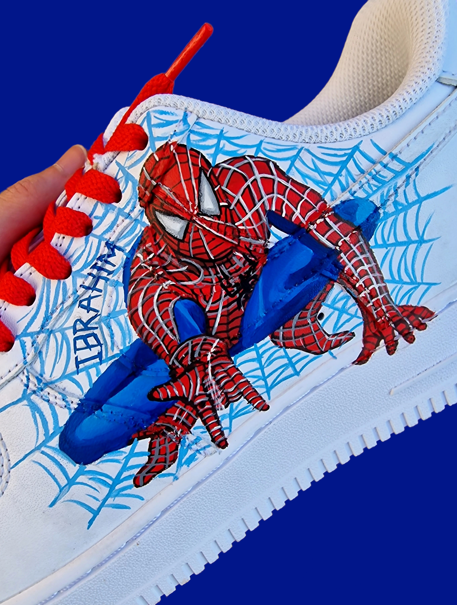 Hand-painted custom Spiderman Nike AF1 kids sneakers with red and black Spiderman portraits, detailed web design, and personalized name on white leather shoes.