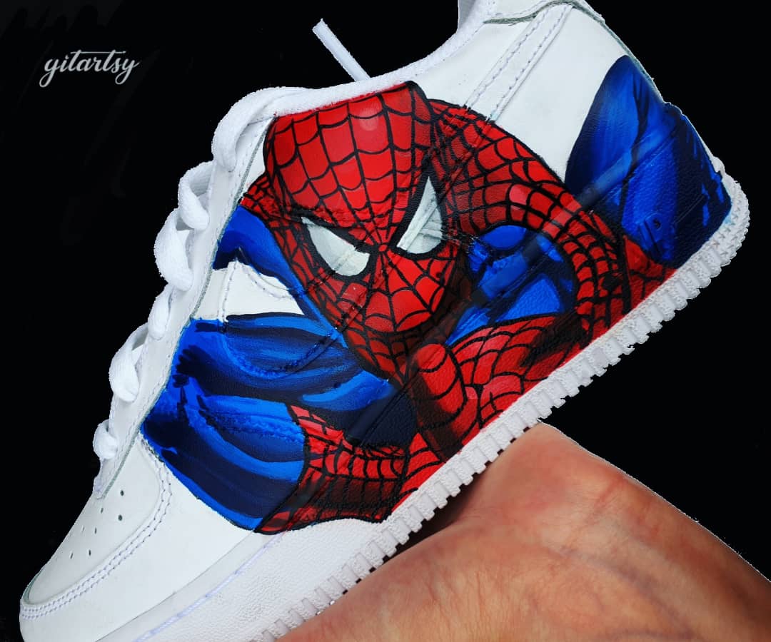 White Nike kids sneakers hand-painted with a vivid Spiderman design featuring red and blue colors, including detailed webbing and dynamic poses on the sides, with a personalized name on the side heel area; perfect for young Marvel fans, custom made by Gitartsy with high-quality waterproof leather paints and sealer for durability.