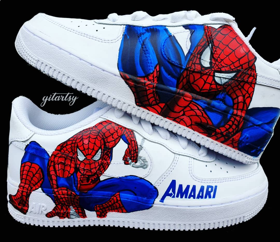 White Nike kids sneakers hand-painted with a vivid Spiderman design featuring red and blue colors, including detailed webbing and dynamic poses on the sides, with a personalized name on the side heel area; perfect for young Marvel fans, custom made by Gitartsy with high-quality waterproof leather paints and sealer for durability.