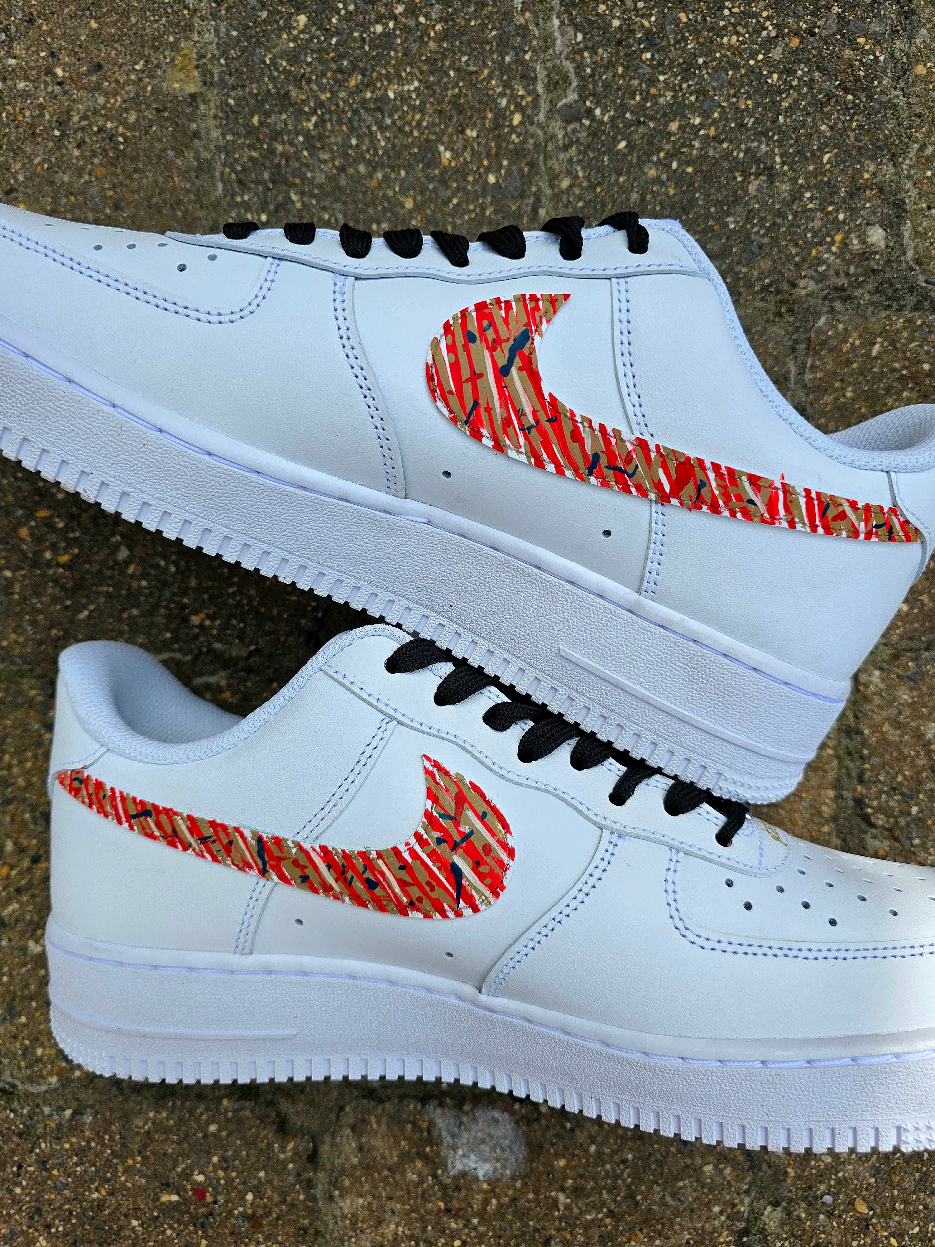 Custom hand-painted Nike Air Force 1 sneakers with Arsenal FC-inspired design, featuring red, gold, and navy brush strokes, personalized details like player name and number, Arsenal logo, and splatter effect art—crafted on a genuine white leather Nike AF1 base by Gitartsy.

