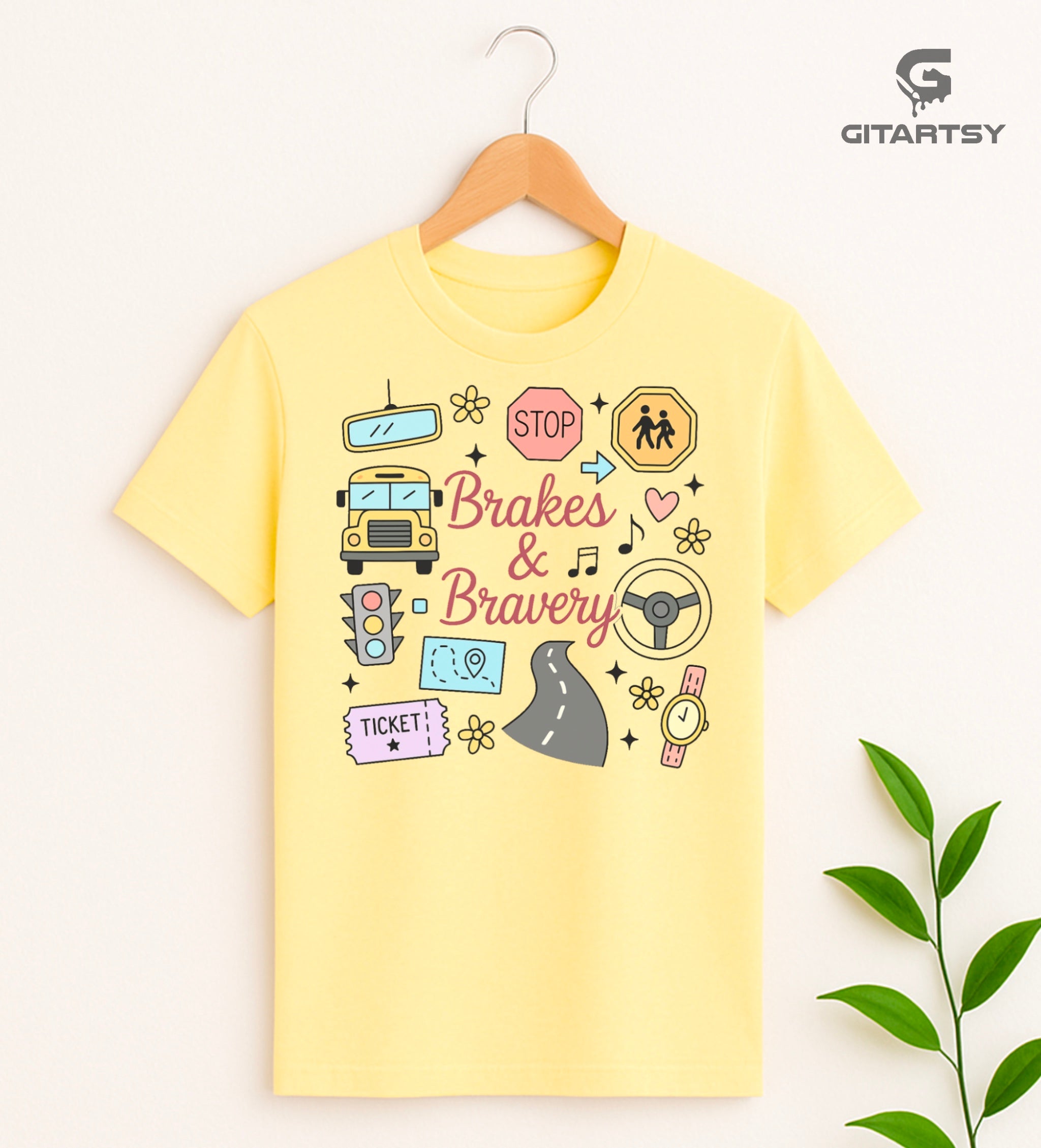 Pastel T-shirt with “Brakes & Bravery” design featuring illustrated school bus, road signs, steering wheel, and driving elements – ideal gift for bus drivers and transport staff