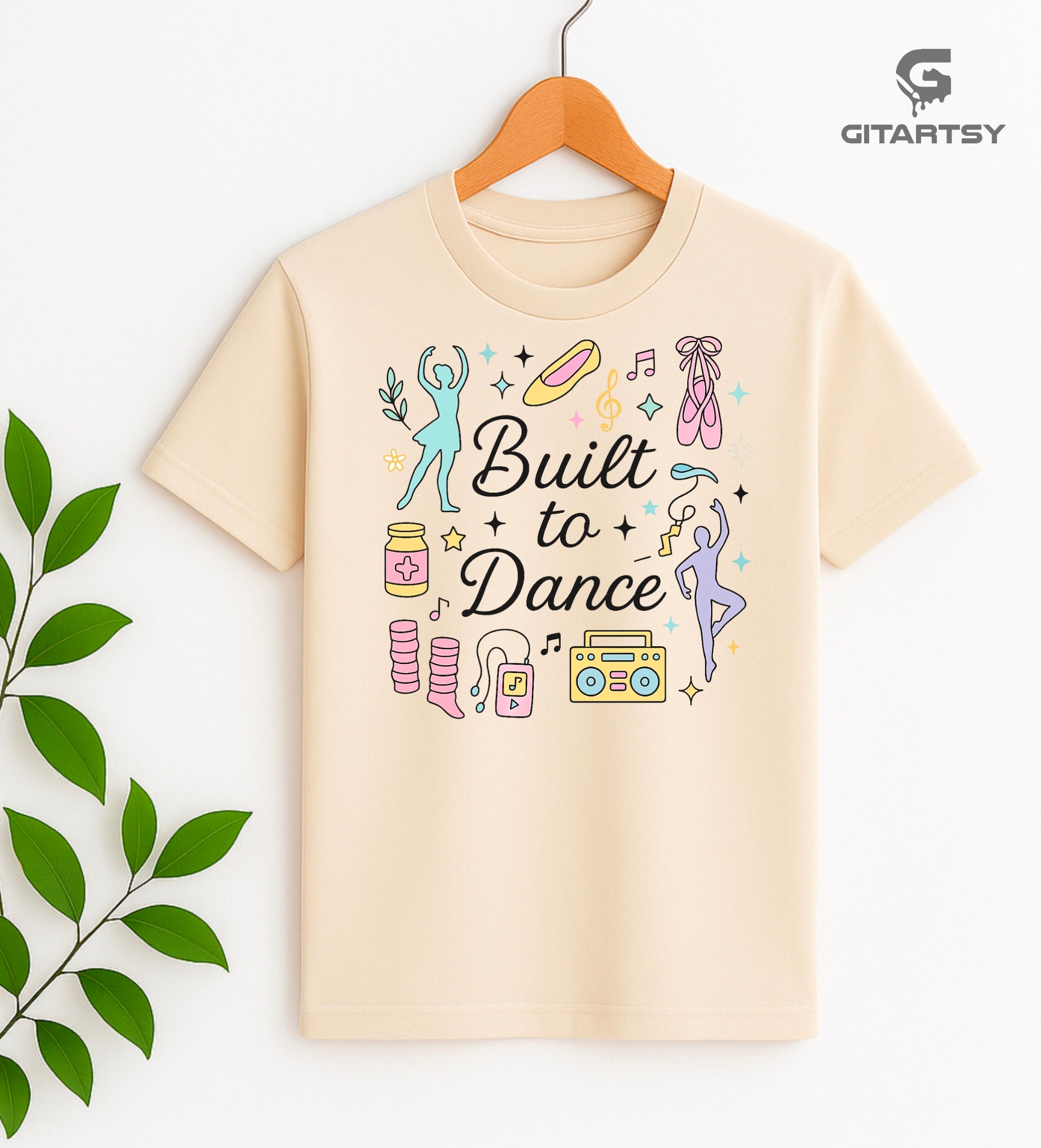Pastel t-shirt with the phrase "Built to Dance" surrounded by dancer silhouettes, ballet shoes, leg warmers, and music symbols – ideal for dance lovers, choreographers, and teachers.