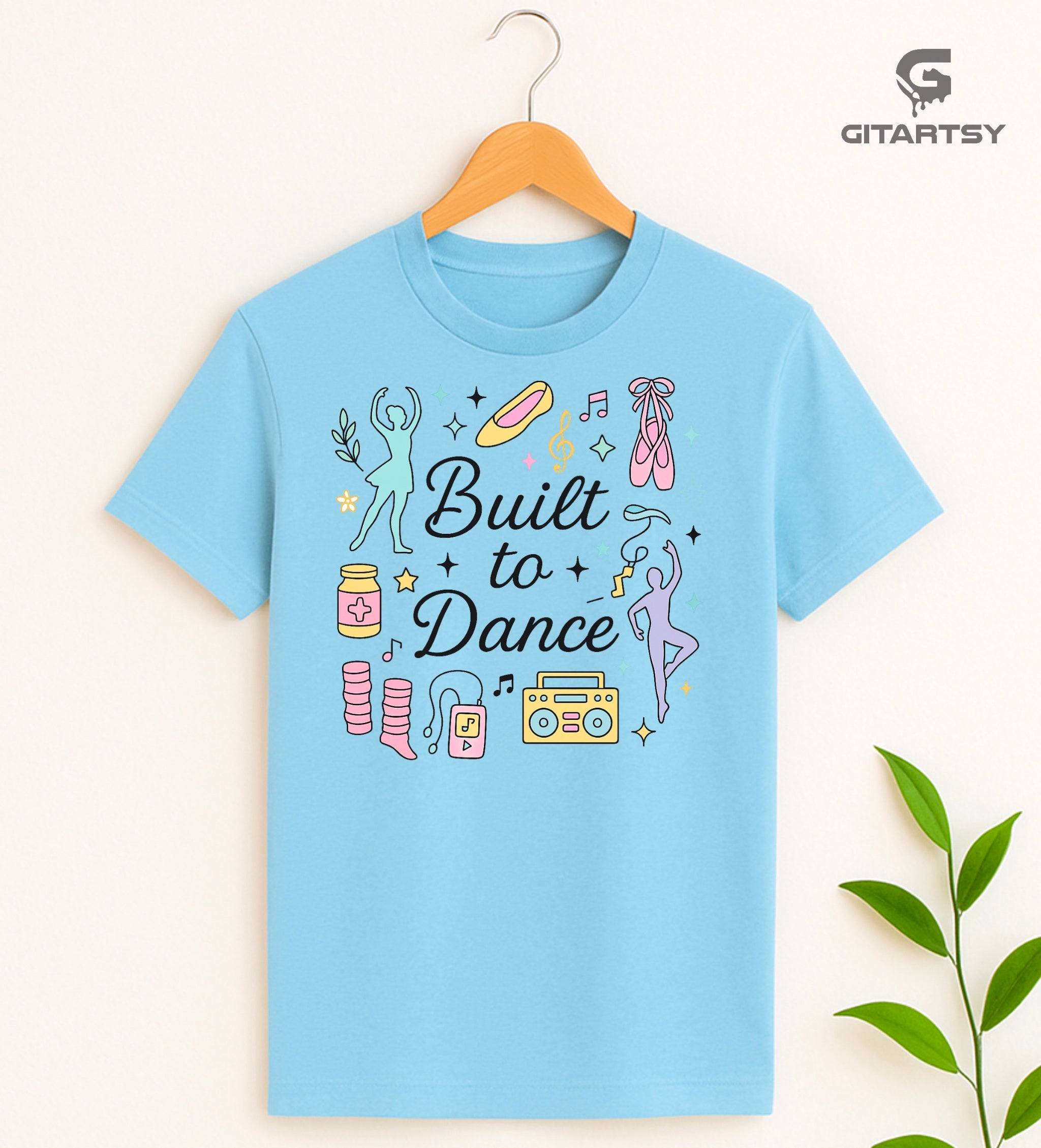 Pastel t-shirt with the phrase "Built to Dance" surrounded by dancer silhouettes, ballet shoes, leg warmers, and music symbols – ideal for dance lovers, choreographers, and teachers.