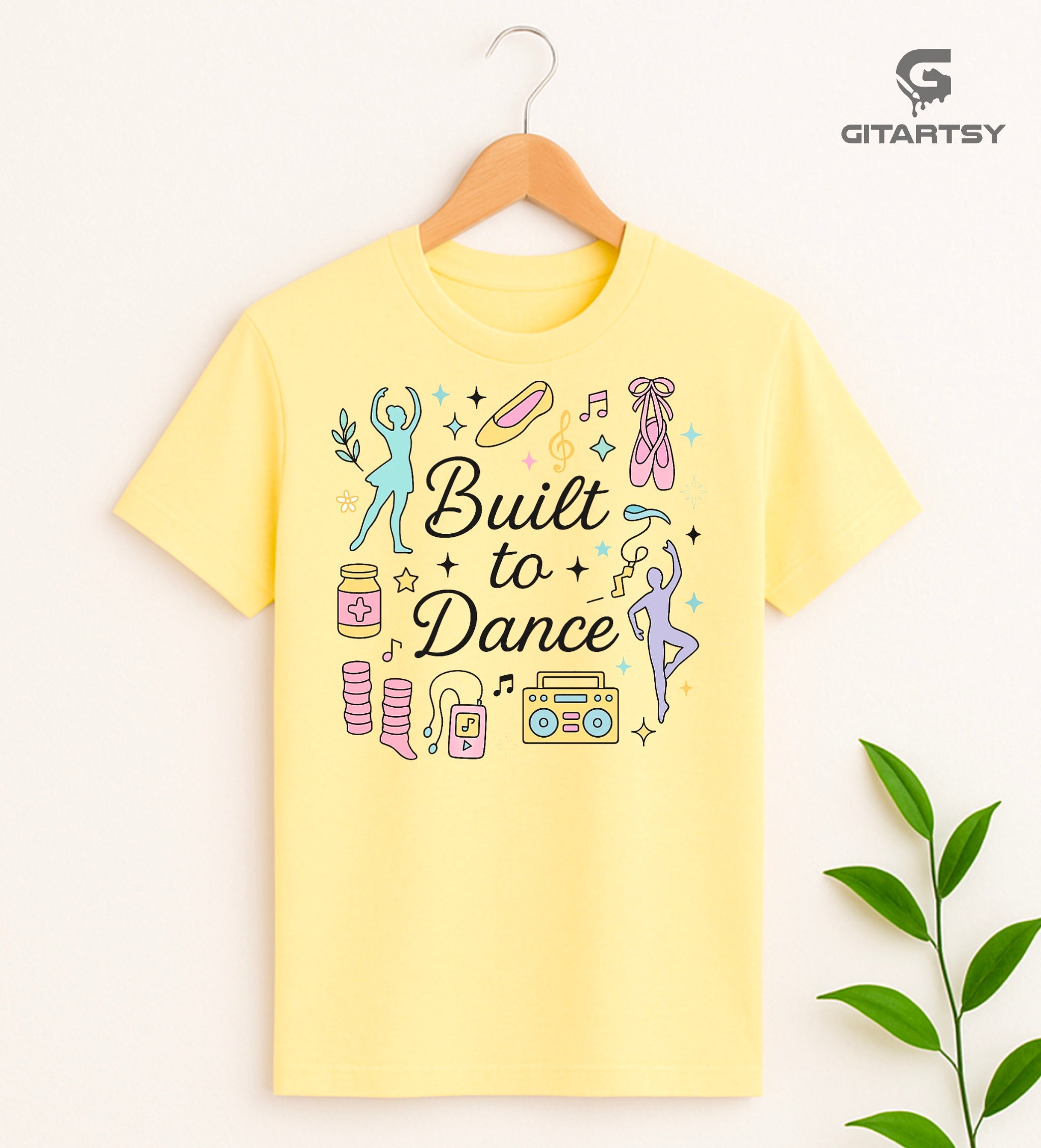 Pastel t-shirt with the phrase "Built to Dance" surrounded by dancer silhouettes, ballet shoes, leg warmers, and music symbols – ideal for dance lovers, choreographers, and teachers.