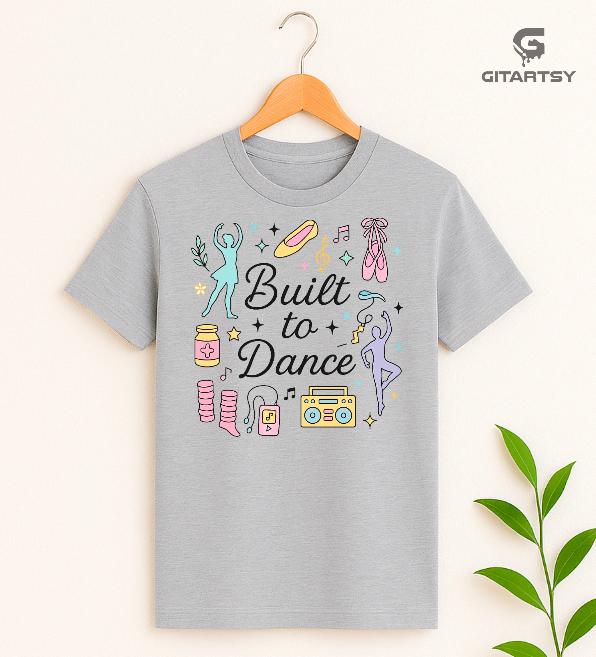 Pastel t-shirt with the phrase "Built to Dance" surrounded by dancer silhouettes, ballet shoes, leg warmers, and music symbols – ideal for dance lovers, choreographers, and teachers.