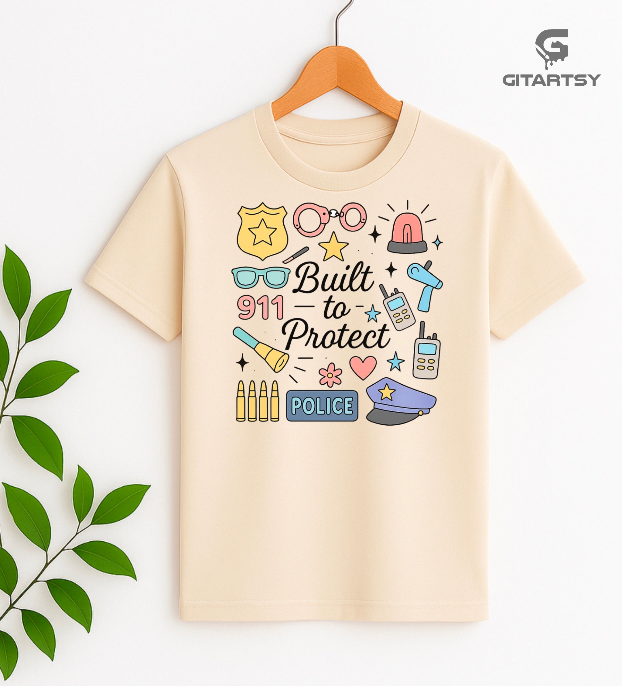 Pastel graphic T-shirt for policewomen with icons like badges, handcuffs, sirens, and 911 – “Built to Protect” slogan in stylish typography.