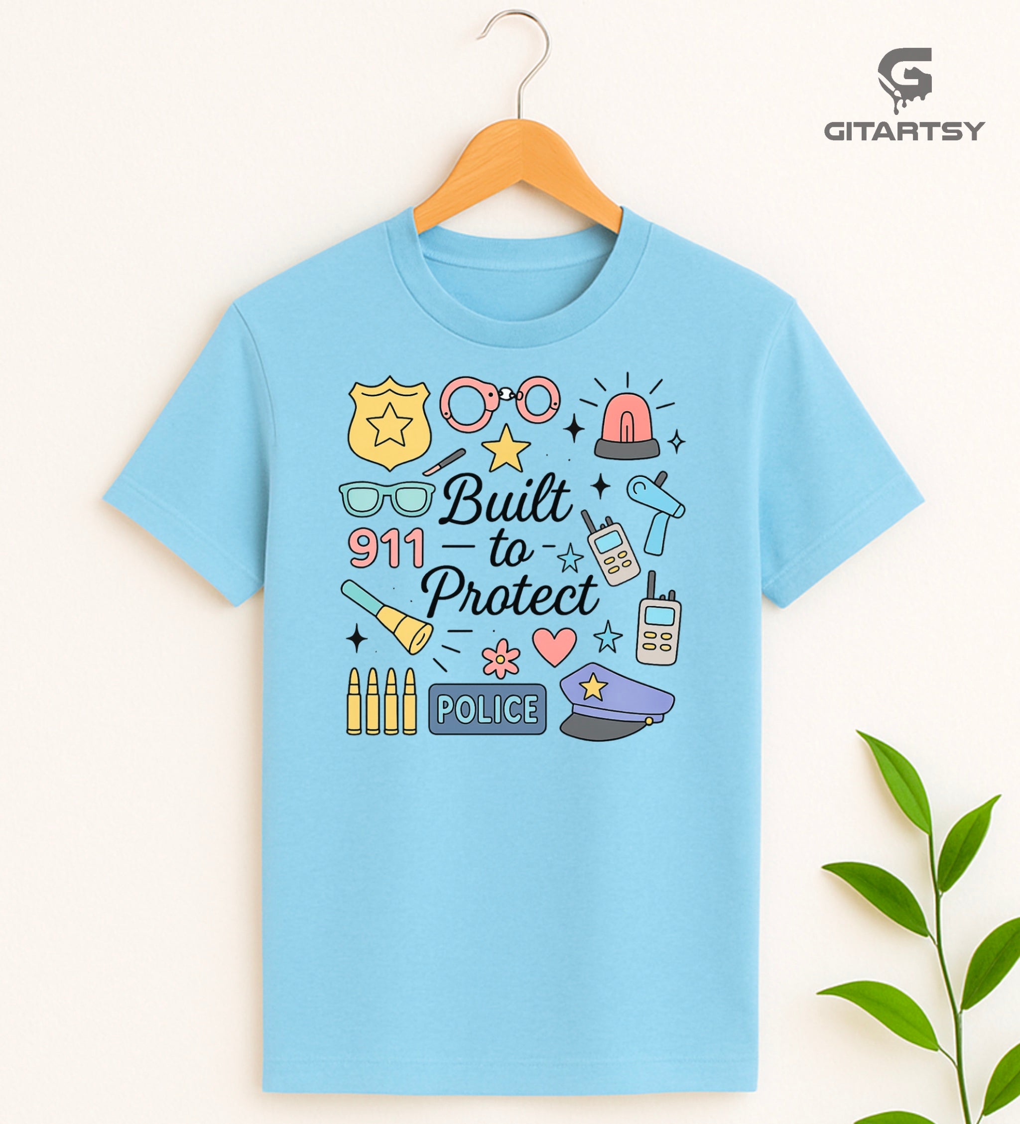 Pastel graphic T-shirt for policewomen with icons like badges, handcuffs, sirens, and 911 – “Built to Protect” slogan in stylish typography.