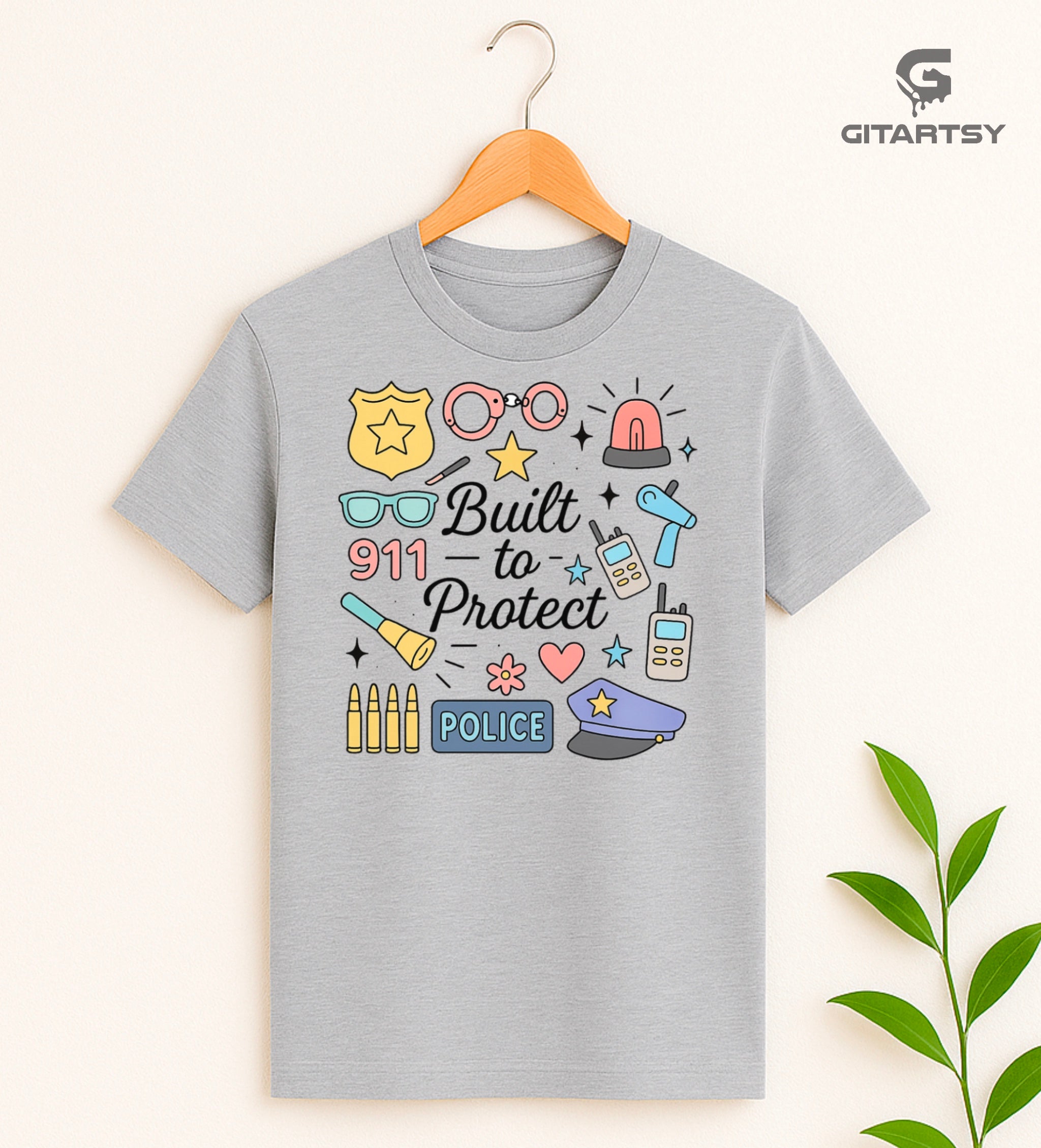 Pastel graphic T-shirt for policewomen with icons like badges, handcuffs, sirens, and 911 – “Built to Protect” slogan in stylish typography.