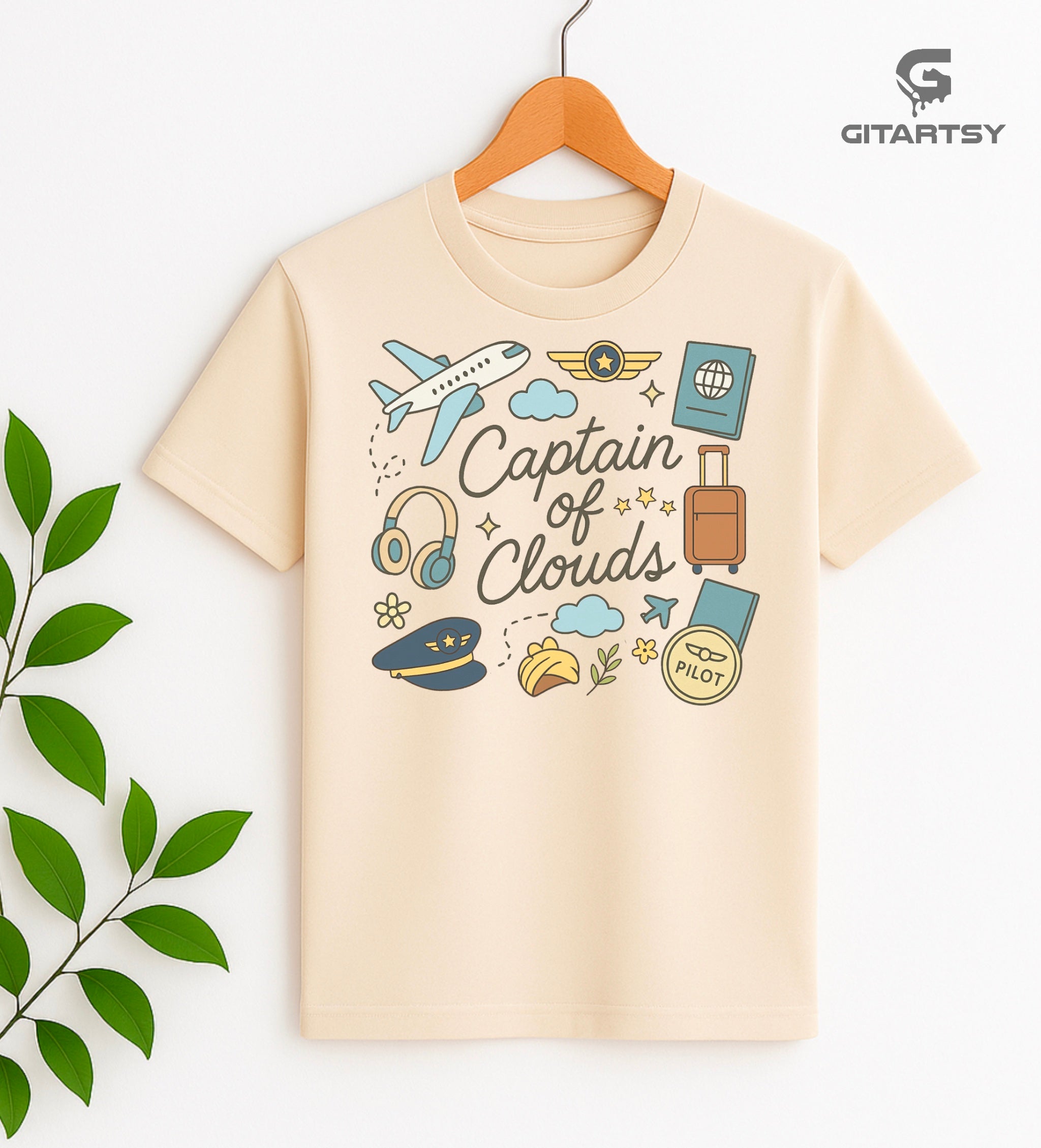 Pastel pilot-themed t-shirt with plane, cloud, headset, and travel icons. "Captain of Clouds" design for aviation lovers and airline crew.