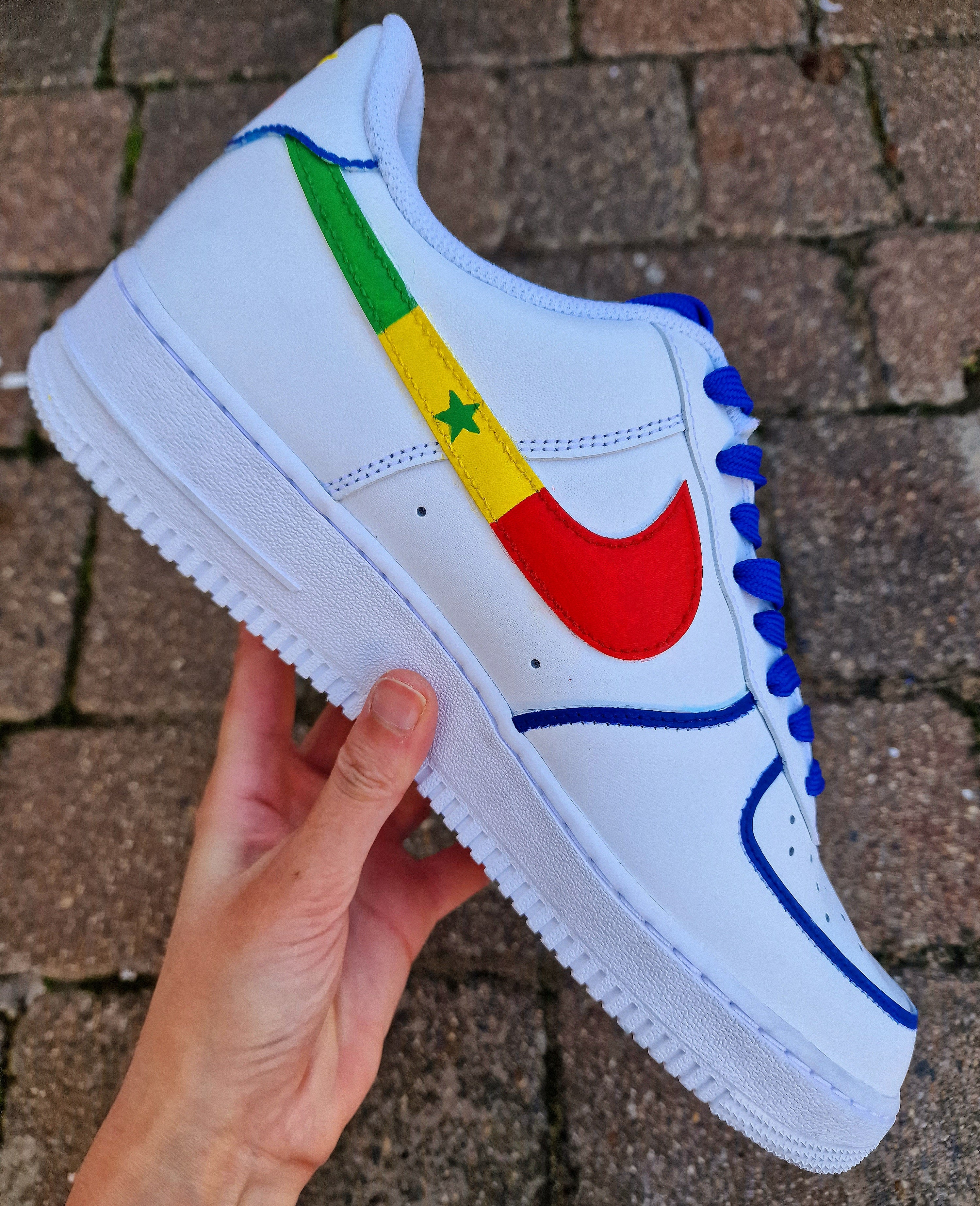Custom hand-painted white sneakers featuring Chelsea FC’s Nicolas Jackson in vivid blue match kit, complete with the club badge and Senegal flag-inspired Nike swoosh. Designed by Gitartsy, the artwork includes realistic player portraits, fine detailing, and premium waterproof paint, making these shoes a perfect blend of fashion and football art.


