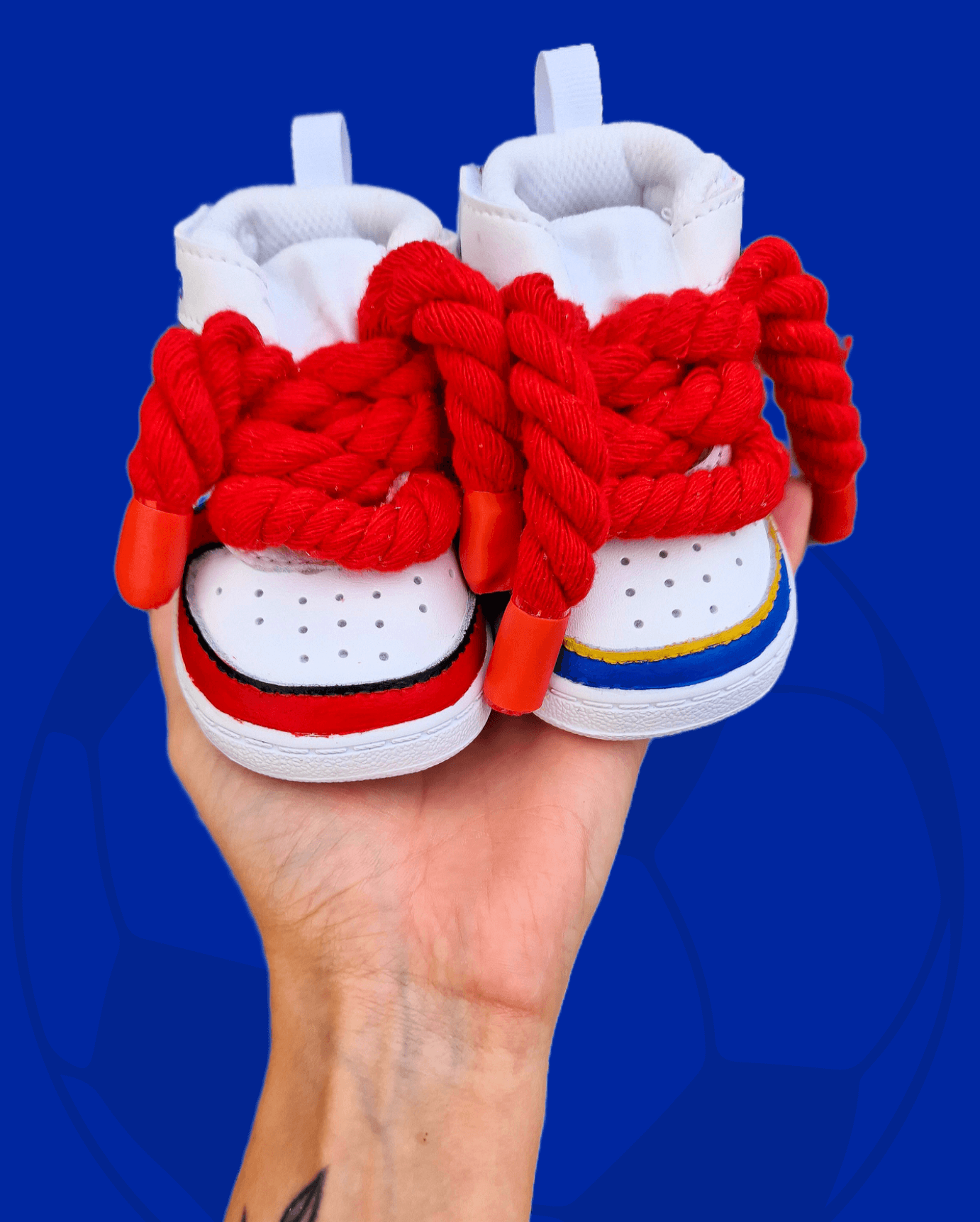 Custom hand-painted baby sneakers inspired by footballer Adama Traoré, featuring FC Barcelona and Fulham FC themes, complete with team logos, jersey illustrations, red braided laces, and personalized strap names on a white baby shoe base.


