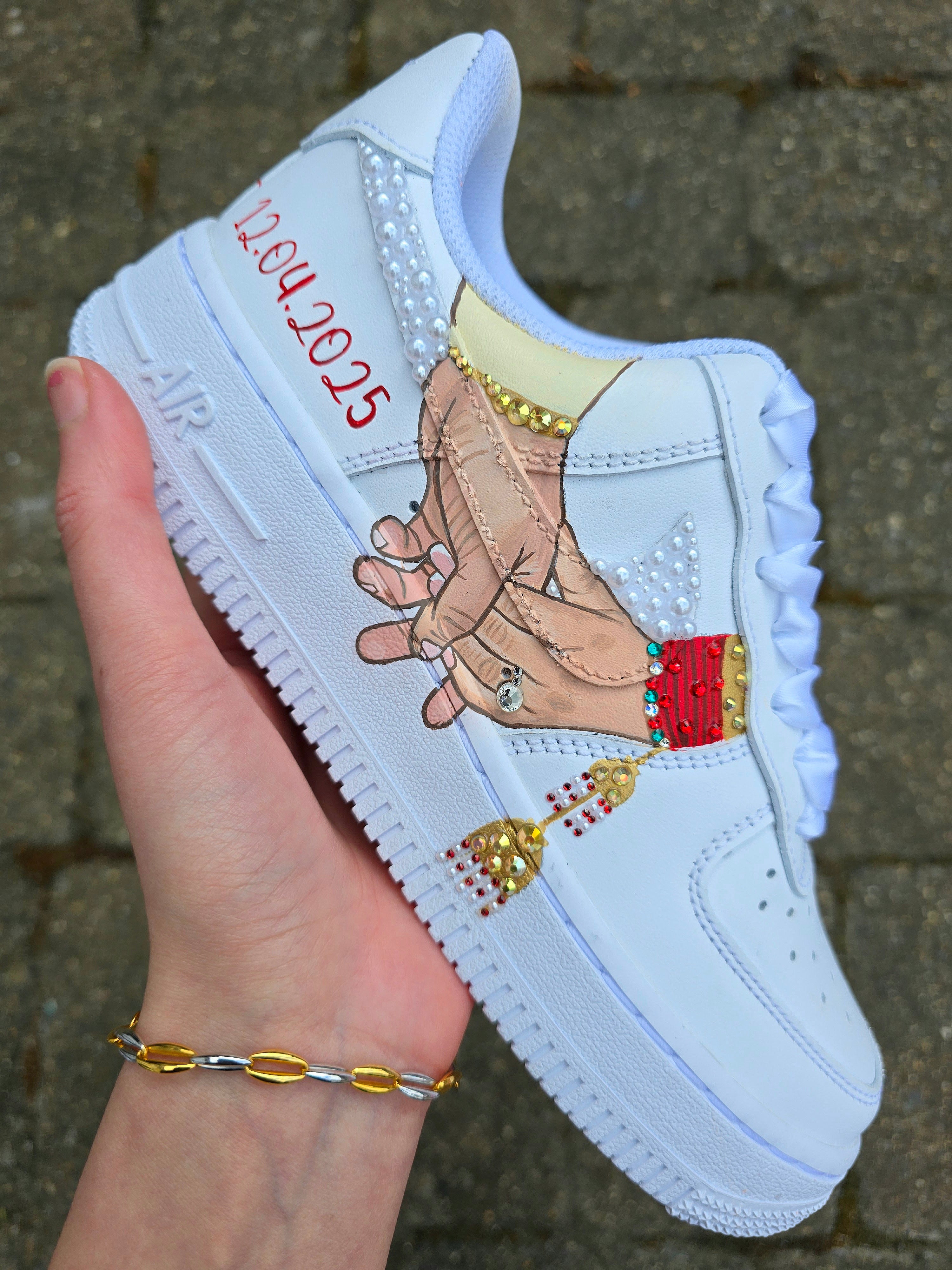 Custom Nike Air Force 1 sneakers hand-painted with a realistic bride and groom portrait, wedding attire details, and personalised touches such as names and dates. Embellished with pearls, rhinestones, and gold accents, these sneakers feature intricate artwork depicting the couple in formal wear and symbolic wedding imagery like clasped hands. Crafted with professional-grade leather paints and sealed for long-lasting wear, these wedding edition shoes combine comfort, style, and sentimental value.

