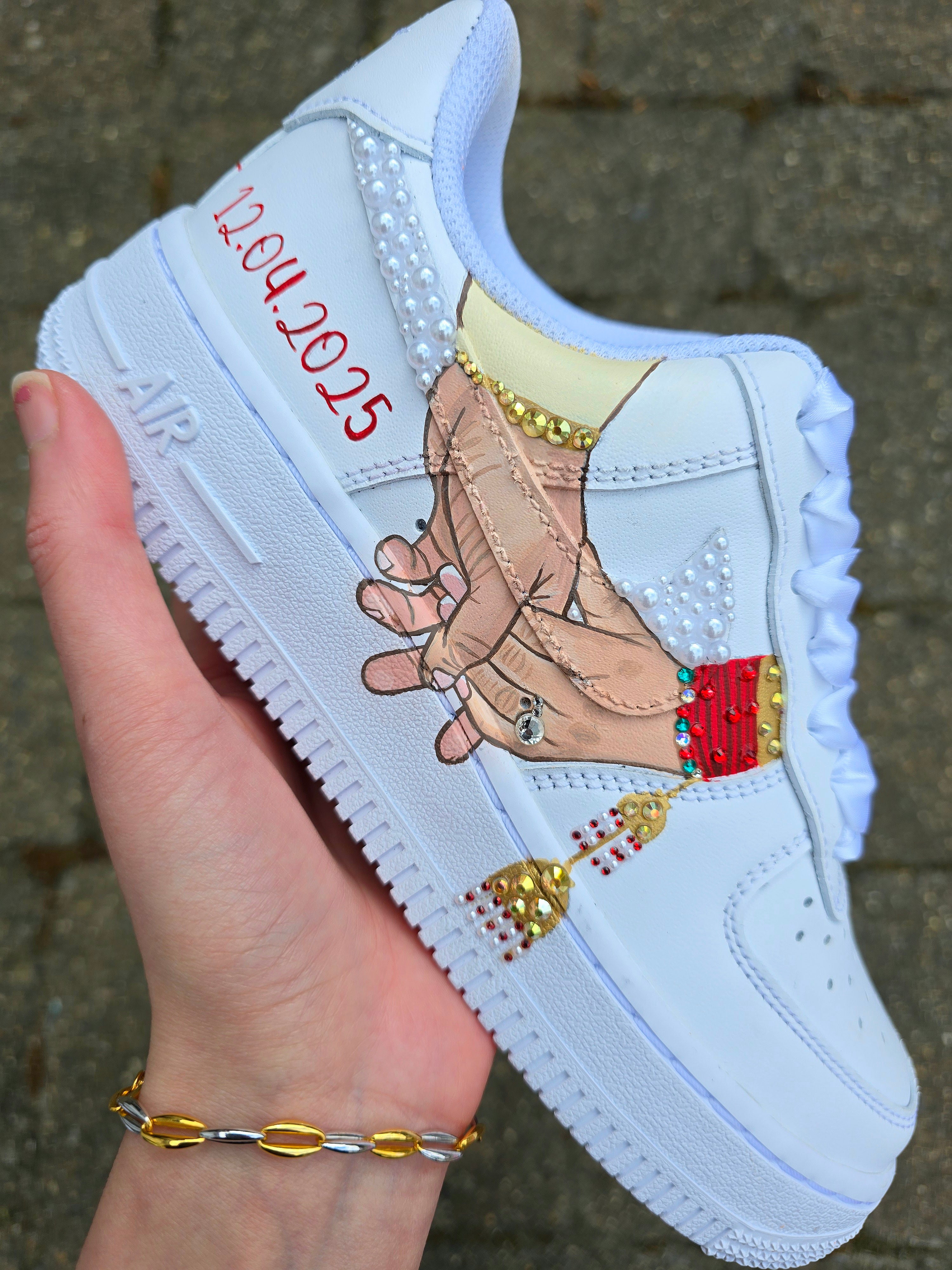 Custom Nike Air Force 1 sneakers hand-painted with a realistic bride and groom portrait, wedding attire details, and personalised touches such as names and dates. Embellished with pearls, rhinestones, and gold accents, these sneakers feature intricate artwork depicting the couple in formal wear and symbolic wedding imagery like clasped hands. Crafted with professional-grade leather paints and sealed for long-lasting wear, these wedding edition shoes combine comfort, style, and sentimental value.

