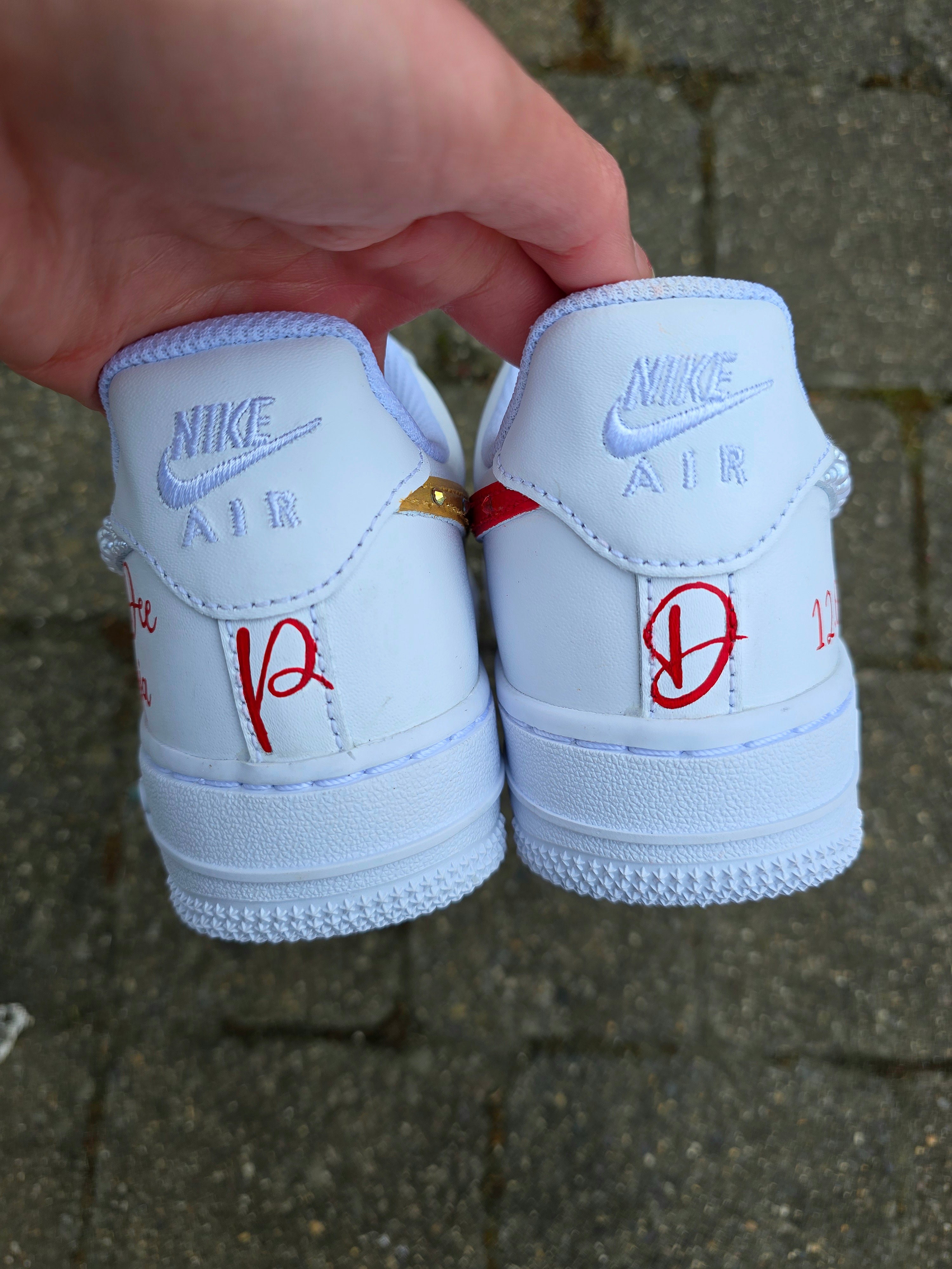Custom Nike Air Force 1 sneakers hand-painted with a realistic bride and groom portrait, wedding attire details, and personalised touches such as names and dates. Embellished with pearls, rhinestones, and gold accents, these sneakers feature intricate artwork depicting the couple in formal wear and symbolic wedding imagery like clasped hands. Crafted with professional-grade leather paints and sealed for long-lasting wear, these wedding edition shoes combine comfort, style, and sentimental value.

