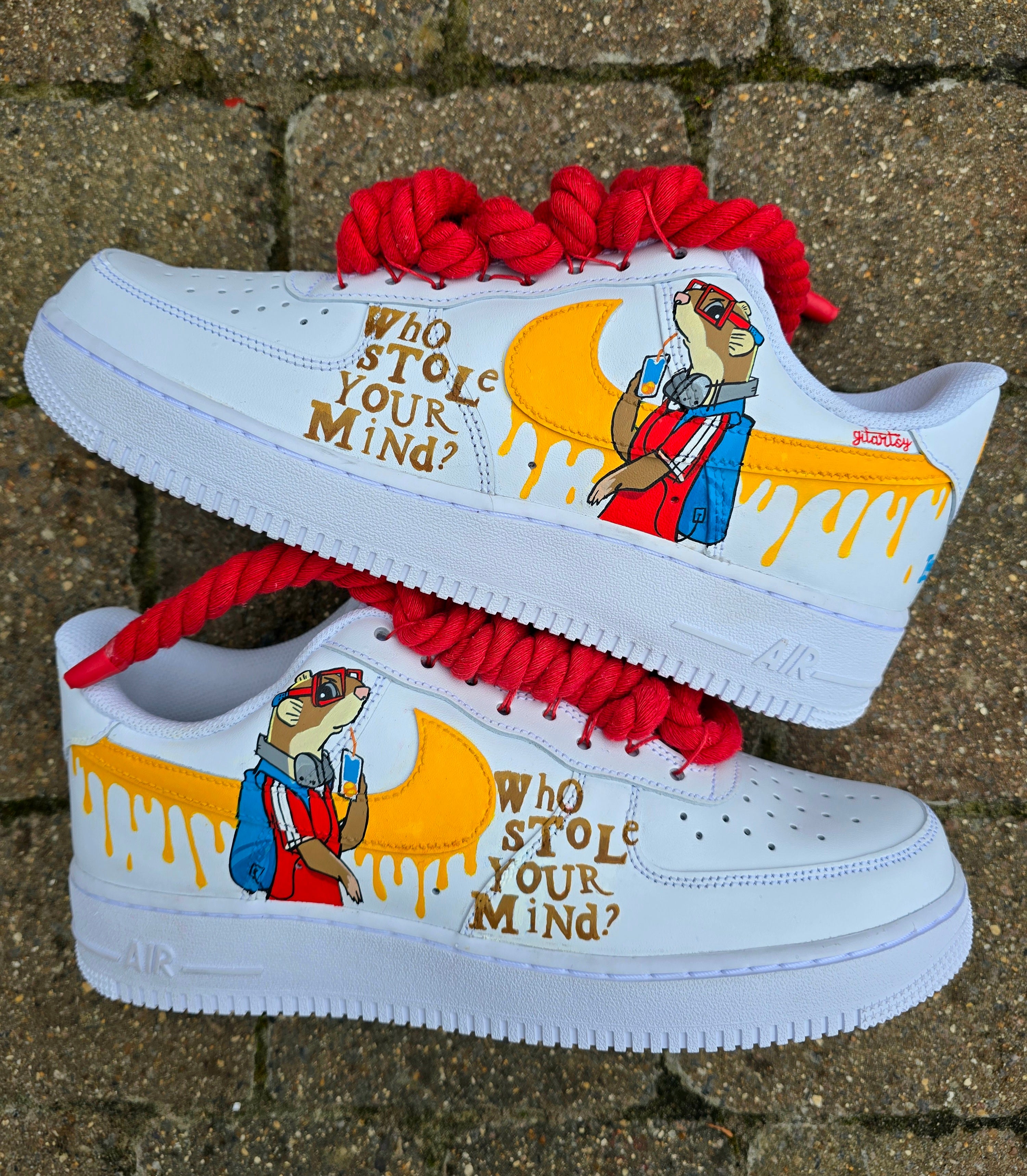 Custom hand-painted Nike Air Force 1 sneakers featuring unique cartoon artwork inspired by the book Who Stole Your Mind? by Being Alphie. The shoes showcase vibrant illustrations, bright yellow swoosh drips, thick red rope laces, and hand-lettered text on premium leather for book lovers, art collectors, and streetwear fans.

