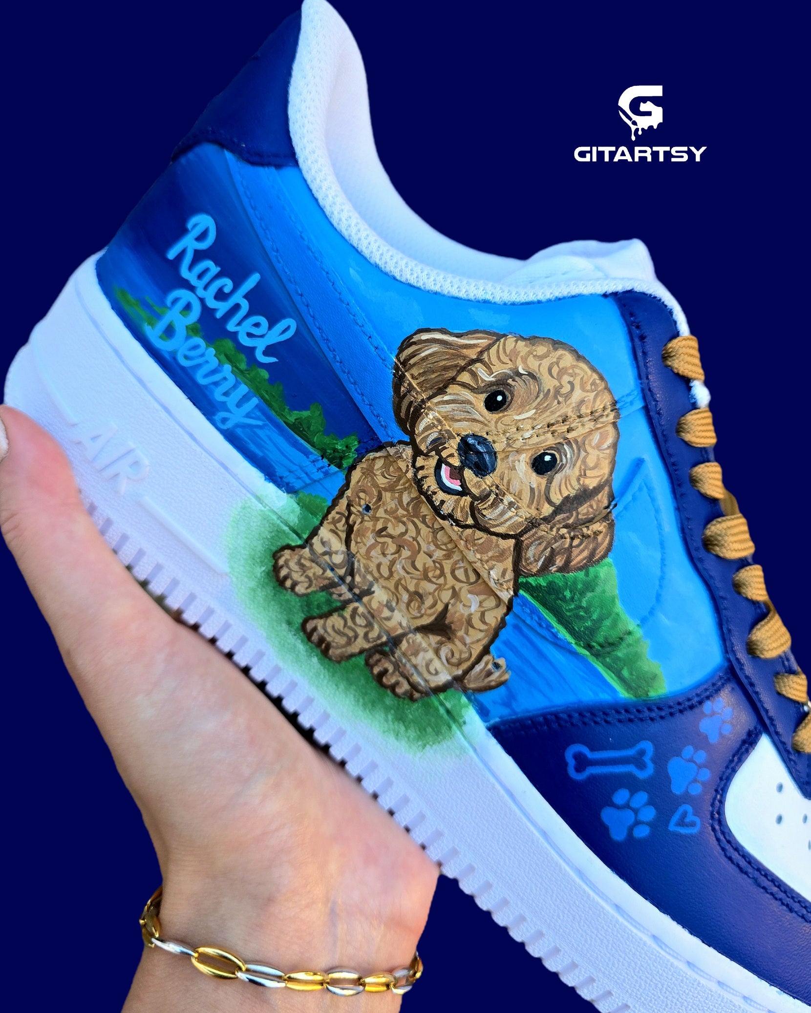 Custom Nike Air Force 1 sneakers 🐾 hand-painted with a detailed toy poodle pet portrait, featuring a caramel-colored curly-haired dog sitting in a grassy field with a blue sky and lake background. Includes the pet’s name in stylish script, paw prints, bones, and heart icons, all painted on a blue and navy color-block base with golden-brown laces. Each pair is personalized to match your pet’s likeness and crafted using durable, waterproof leather paints, making them wearable art for dog lovers.

