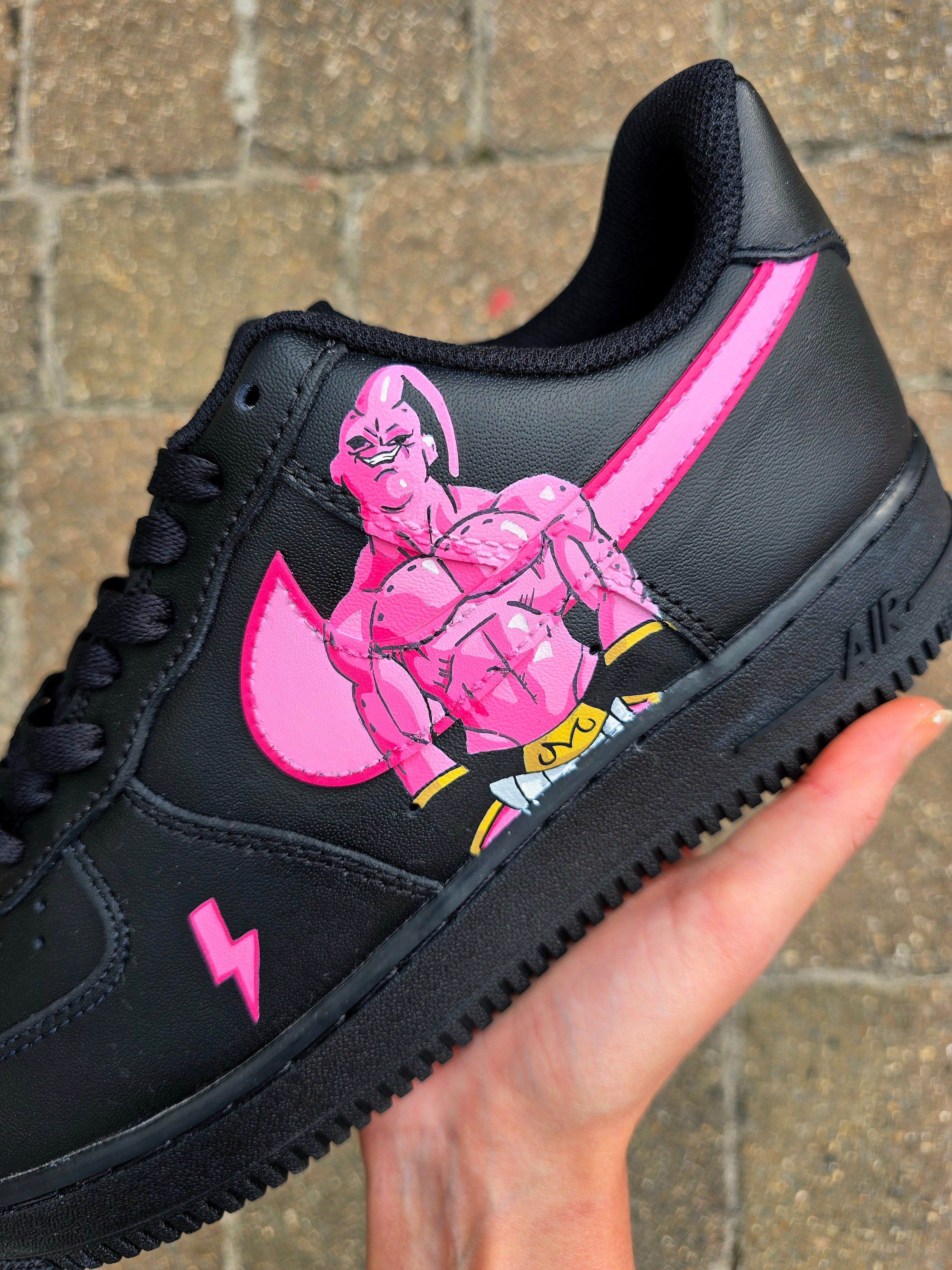 Custom Dragon Ball Z Nike Air Force 1 sneakers featuring hand-painted anime artwork of Majin Buu and Super Saiyan Goku. Black leather base with pink and yellow accents, lightning bolt details, and high-quality, waterproof custom paint job.

