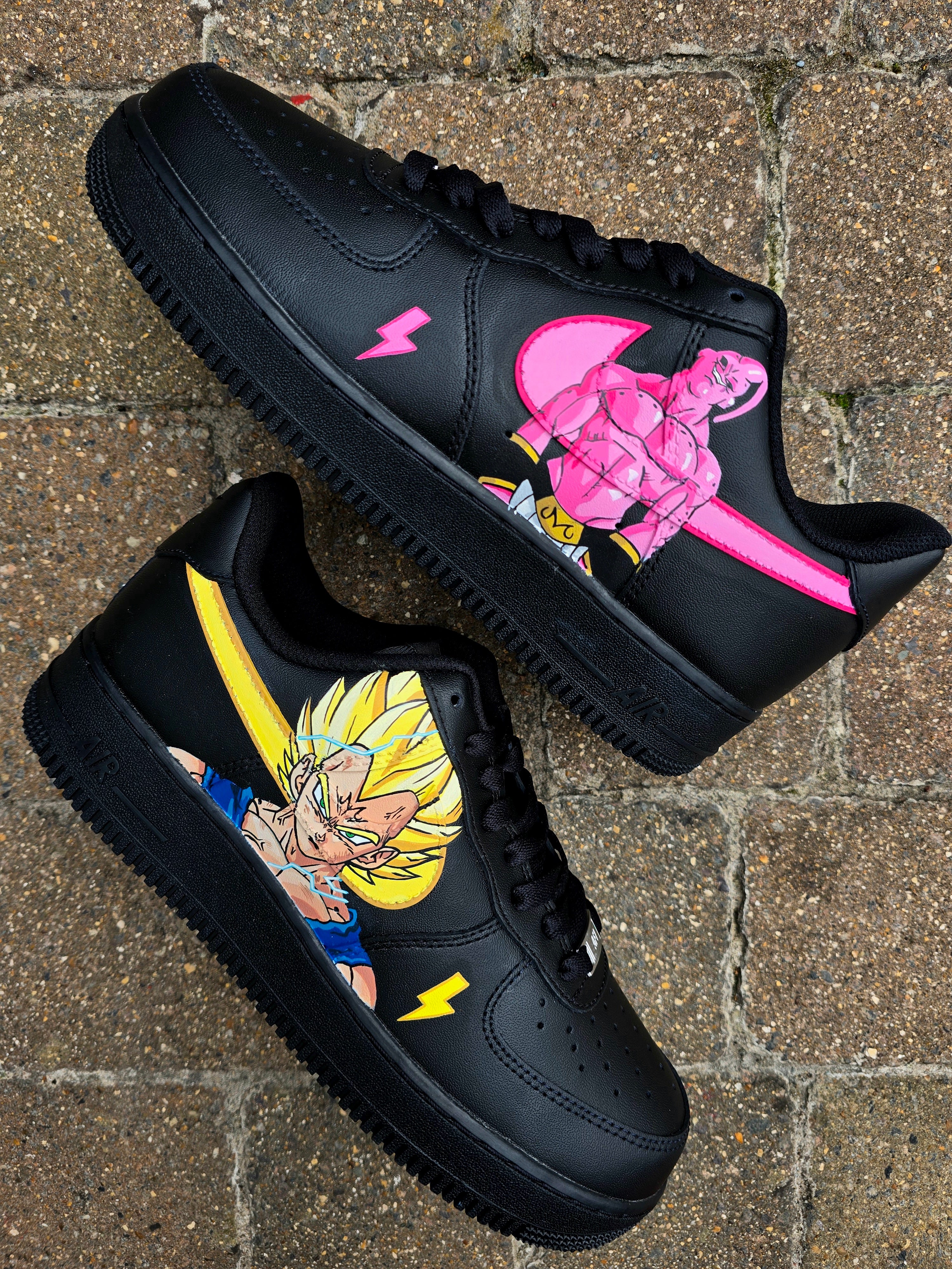 Custom Dragon Ball Z Nike Air Force 1 sneakers featuring hand-painted anime artwork of Majin Buu and Super Saiyan Goku. Black leather base with pink and yellow accents, lightning bolt details, and high-quality, waterproof custom paint job.


