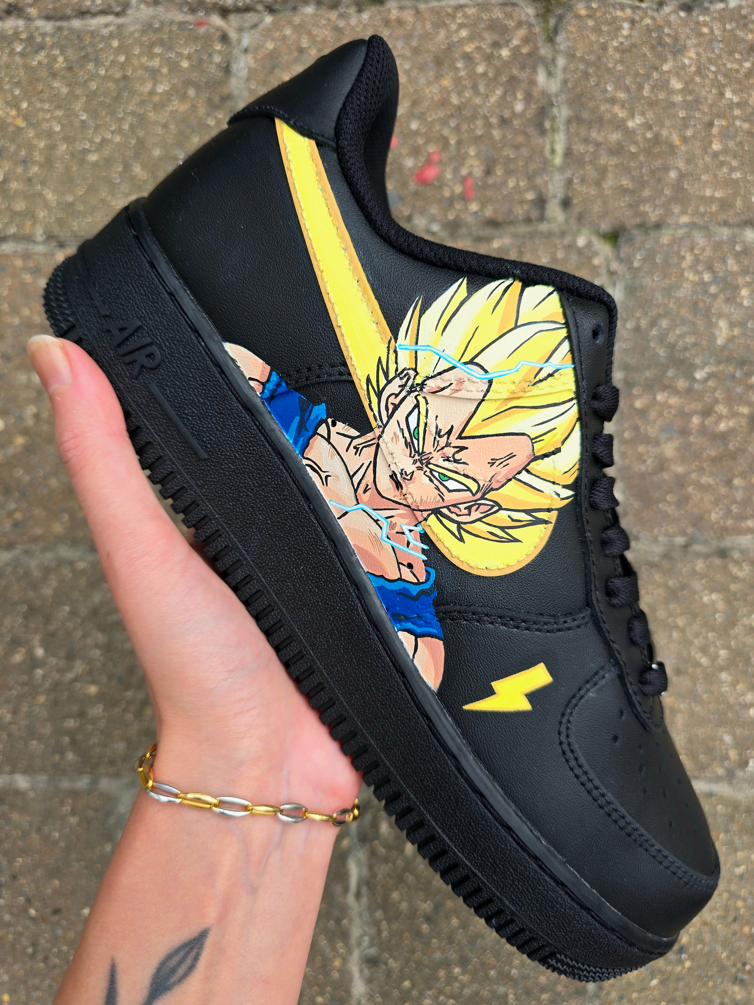 Custom Dragon Ball Z Nike Air Force 1 sneakers featuring hand-painted anime artwork of Majin Buu and Super Saiyan Goku. Black leather base with pink and yellow accents, lightning bolt details, and high-quality, waterproof custom paint job.

