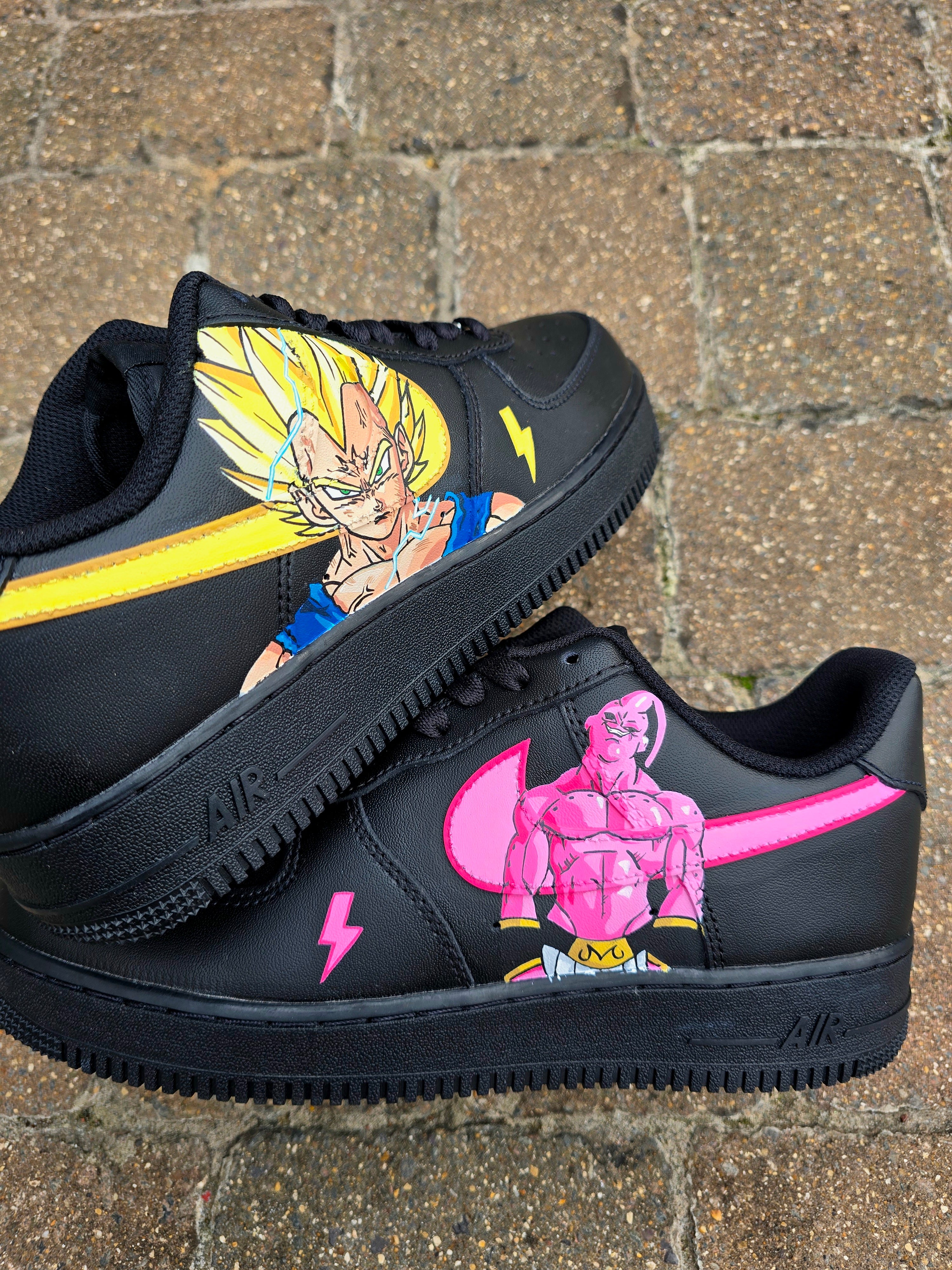 Custom Dragon Ball Z Nike Air Force 1 sneakers featuring hand-painted anime artwork of Majin Buu and Super Saiyan Goku. Black leather base with pink and yellow accents, lightning bolt details, and high-quality, waterproof custom paint job.

