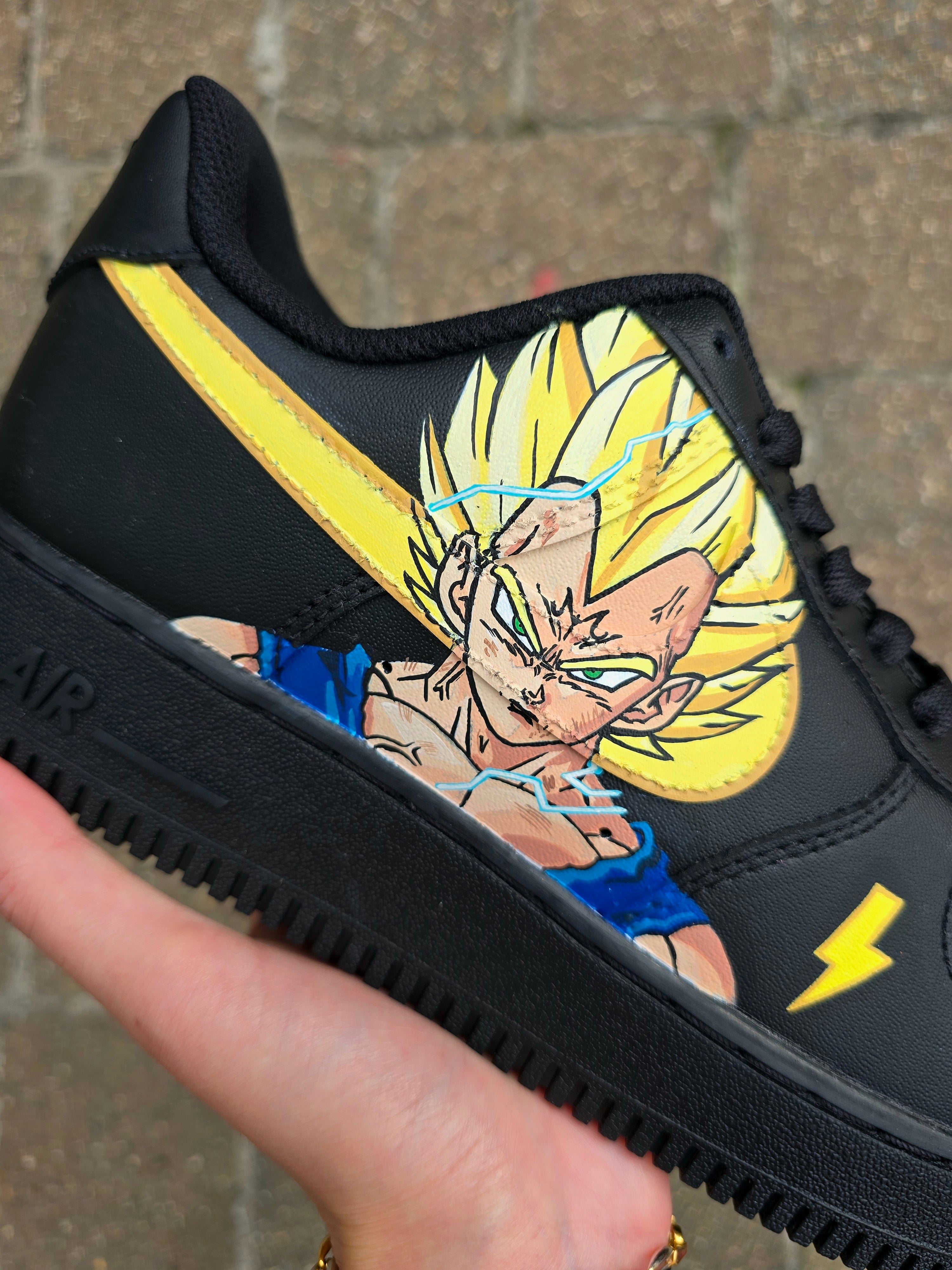 Custom Dragon Ball Z Nike Air Force 1 sneakers featuring hand-painted anime artwork of Majin Buu and Super Saiyan Goku. Black leather base with pink and yellow accents, lightning bolt details, and high-quality, waterproof custom paint job.

