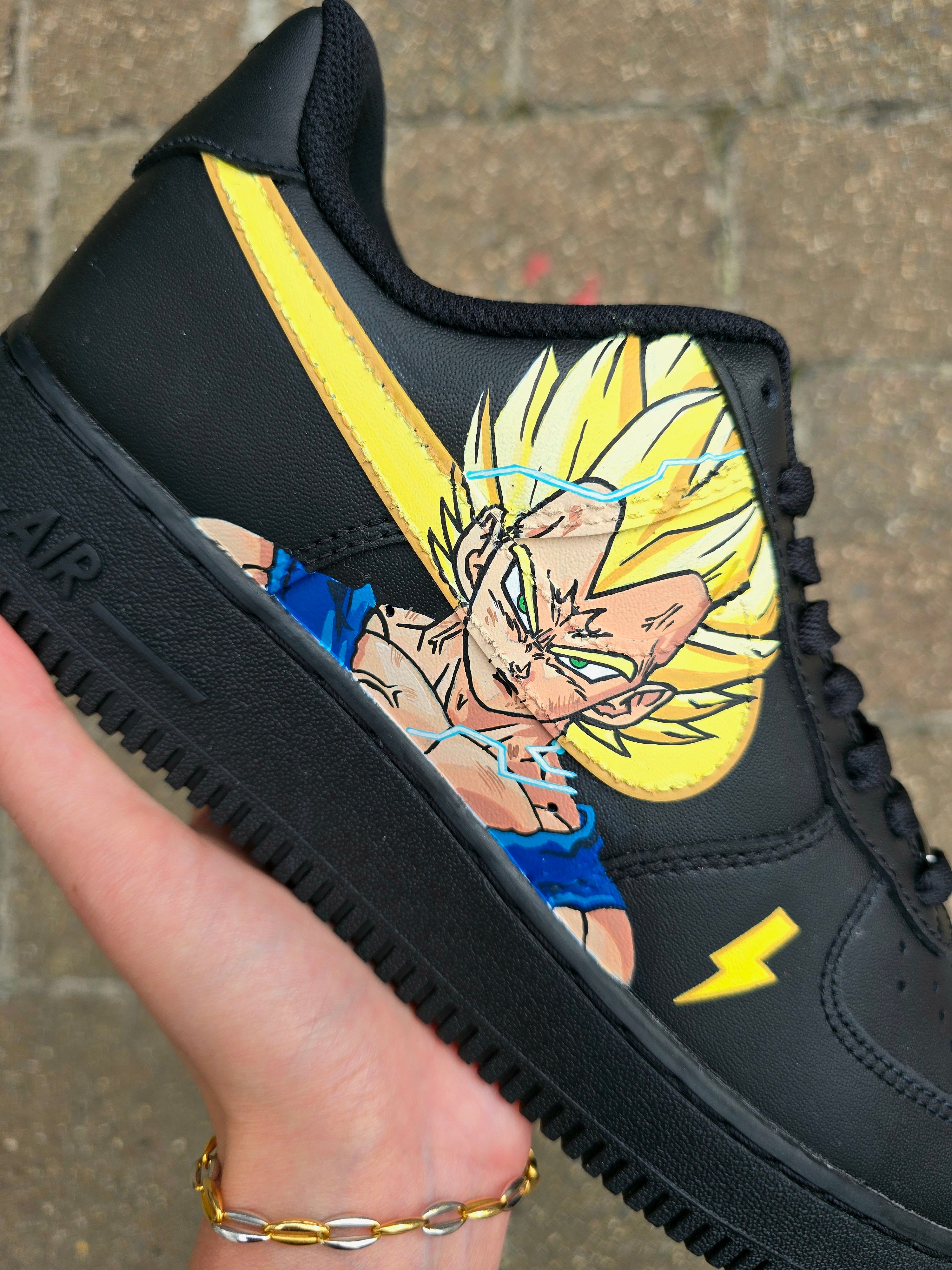 Custom Dragon Ball Z Nike Air Force 1 sneakers featuring hand-painted anime artwork of Majin Buu and Super Saiyan Goku. Black leather base with pink and yellow accents, lightning bolt details, and high-quality, waterproof custom paint job.

