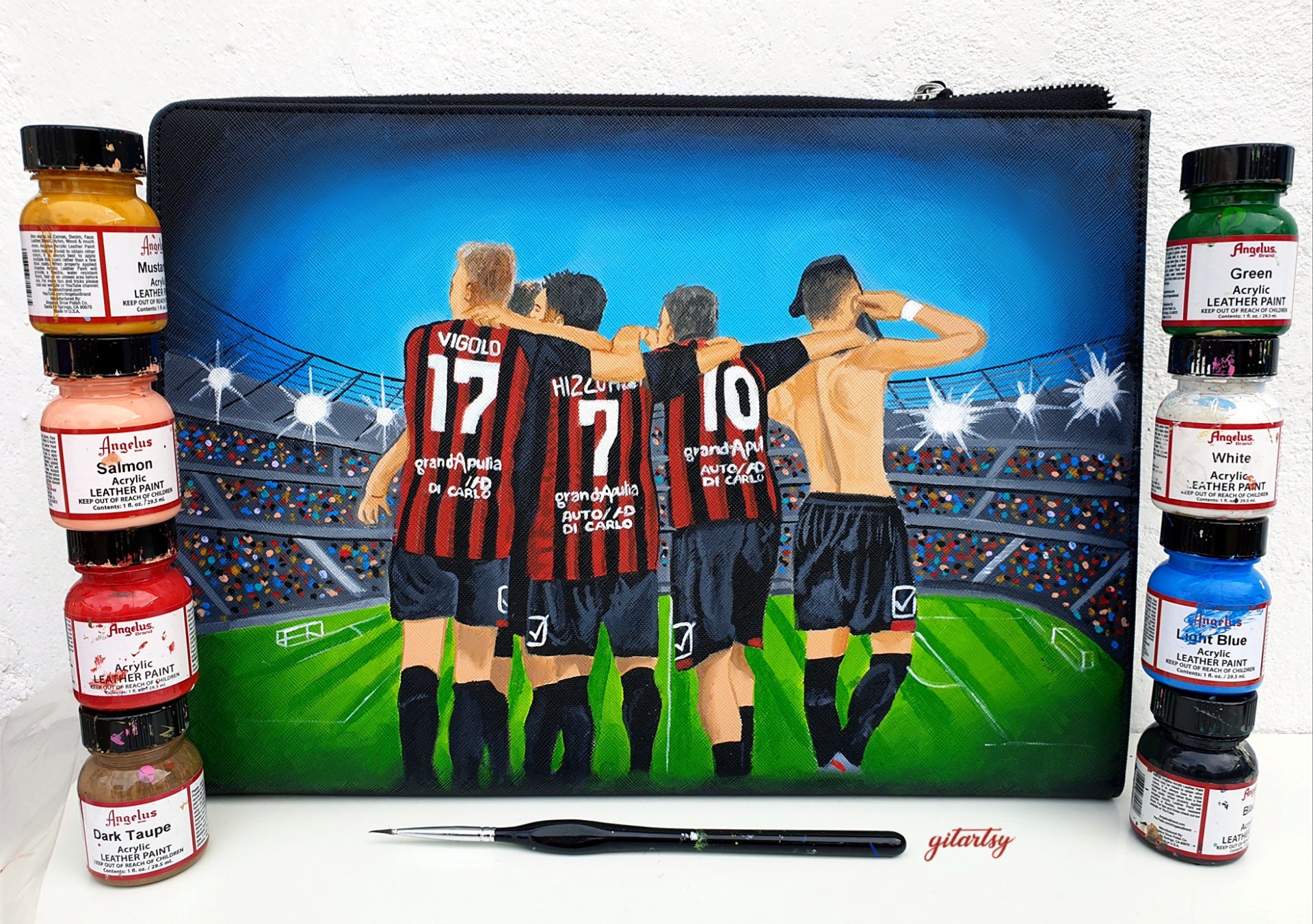 Custom hand-painted footballer artwork wallet depicting four players in red and black striped jerseys with names and numbers, standing arm-in-arm on a stadium field under bright lights, perfect for football fans and players, crafted on a black canvas zippered pouch with vivid colors and intricate details.

