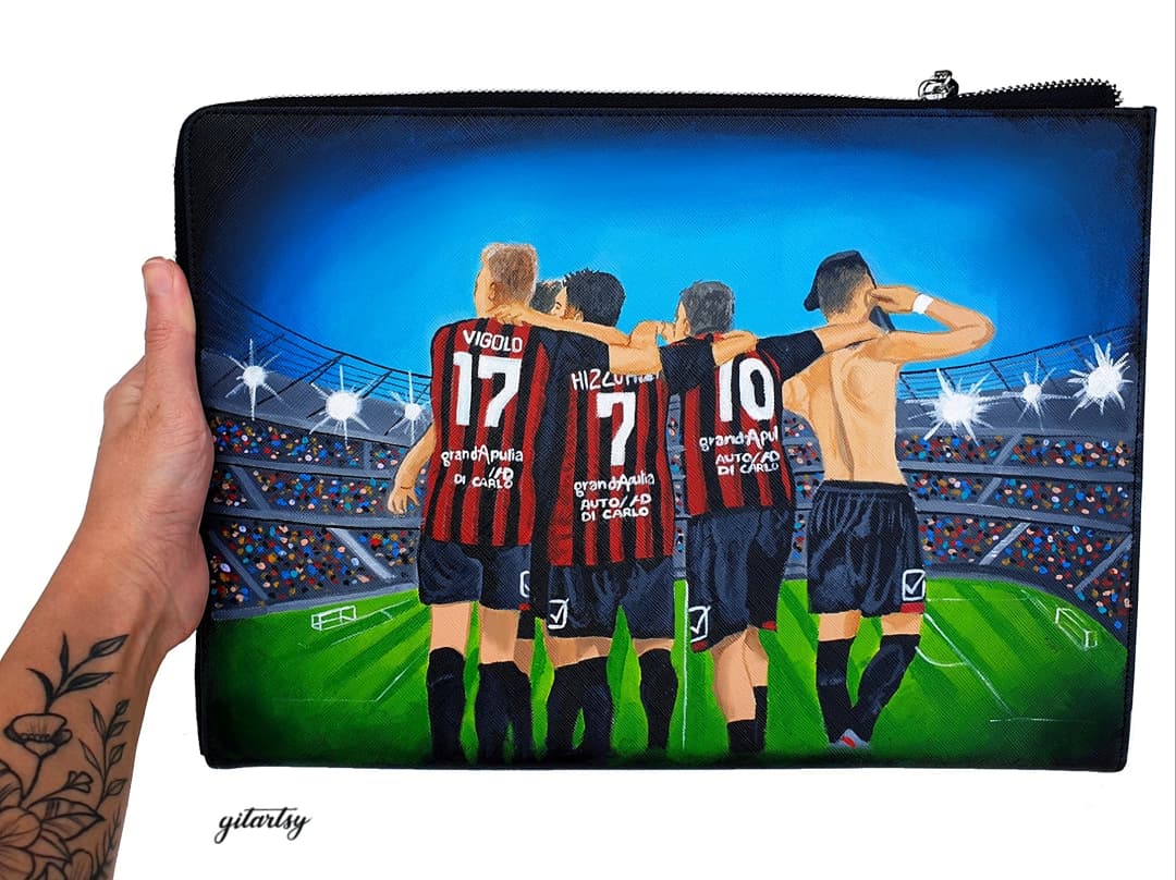 Custom hand-painted footballer artwork wallet depicting four players in red and black striped jerseys with names and numbers, standing arm-in-arm on a stadium field under bright lights, perfect for football fans and players, crafted on a black canvas zippered pouch with vivid colors and intricate details.


