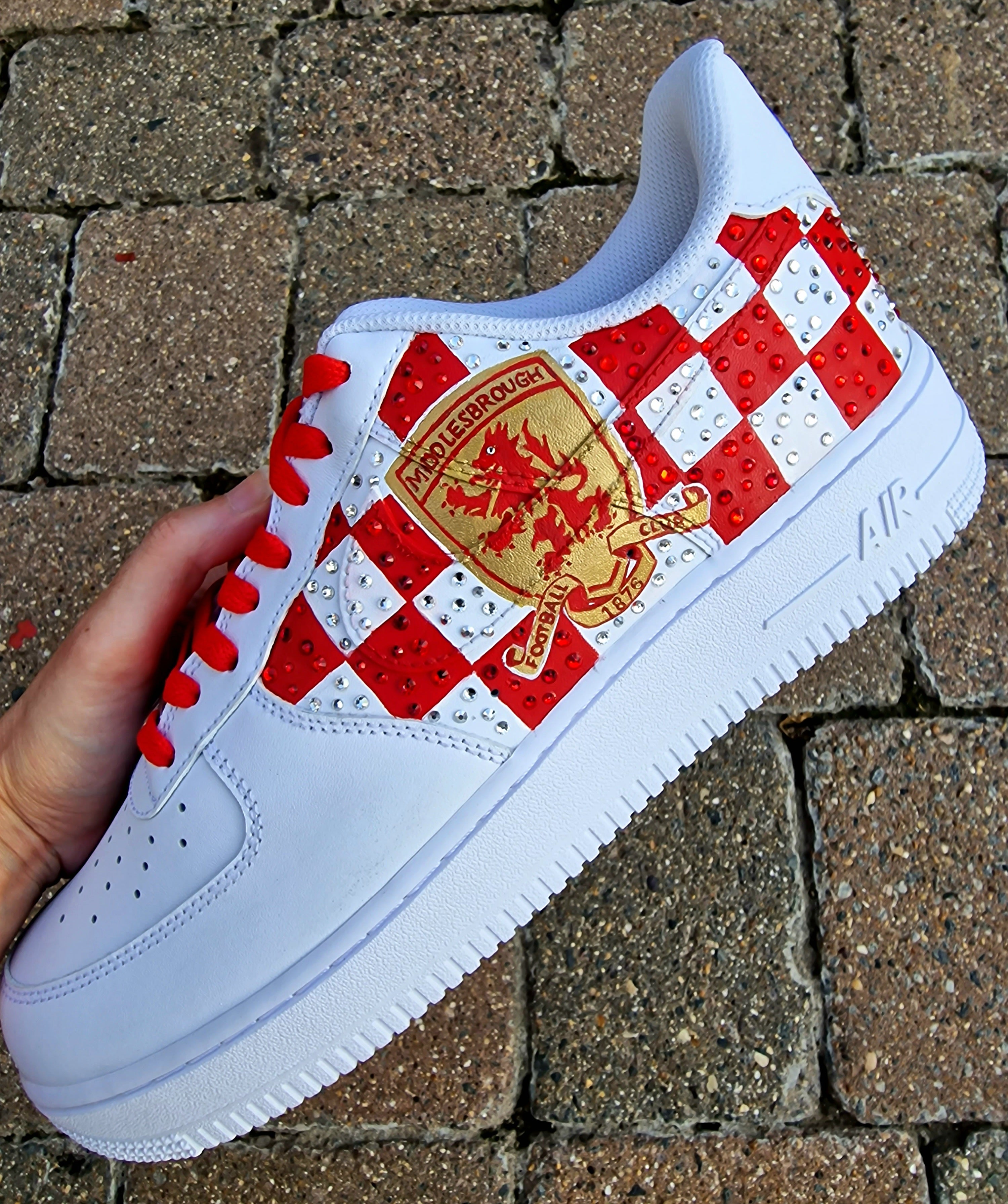 Custom hand-painted sneakers featuring Middlesbrough FC crest, red-and-white checkered pattern with stud embellishments, and detailed Riverside Stadium artwork. White base sneakers with red laces, designed by Gitartsy for football fans, sneaker collectors, and Boro supporters.

