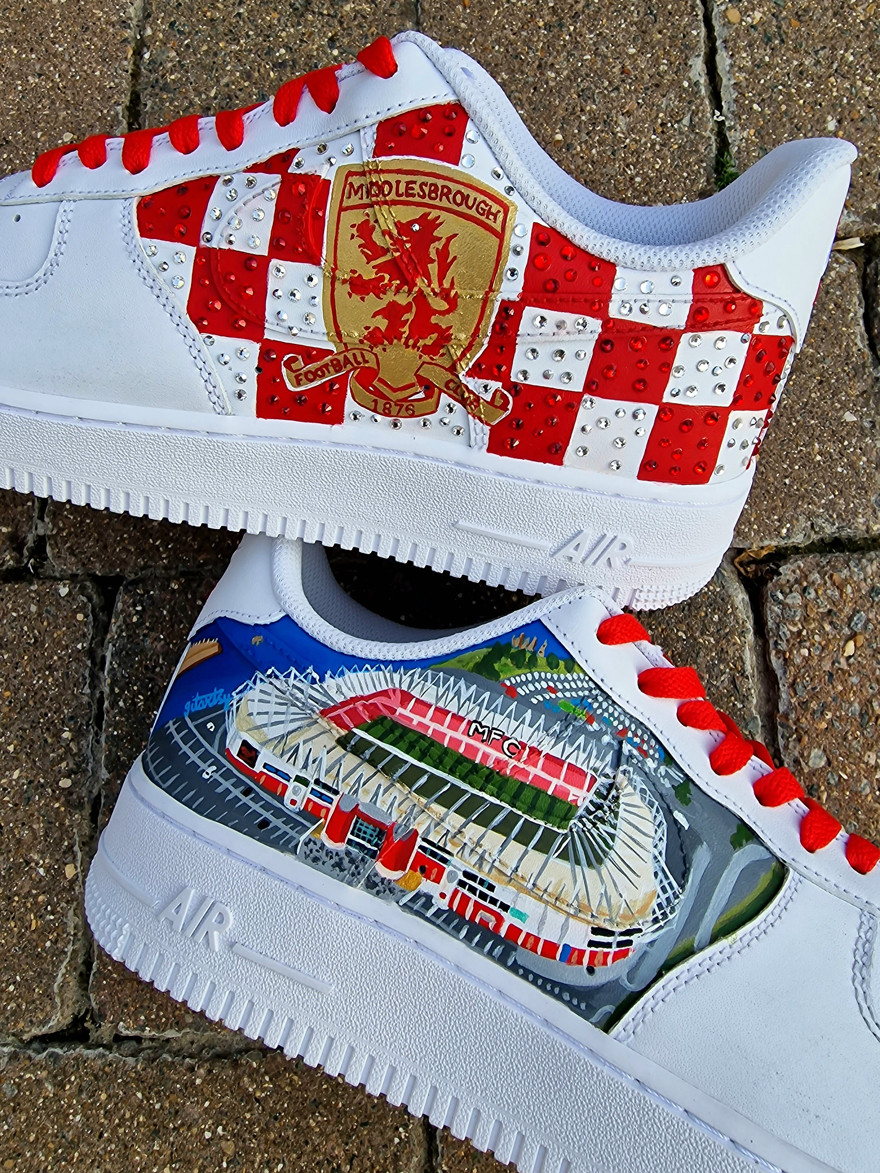 Custom hand-painted sneakers featuring Middlesbrough FC crest, red-and-white checkered pattern with stud embellishments, and detailed Riverside Stadium artwork. White base sneakers with red laces, designed by Gitartsy for football fans, sneaker collectors, and Boro supporters.

