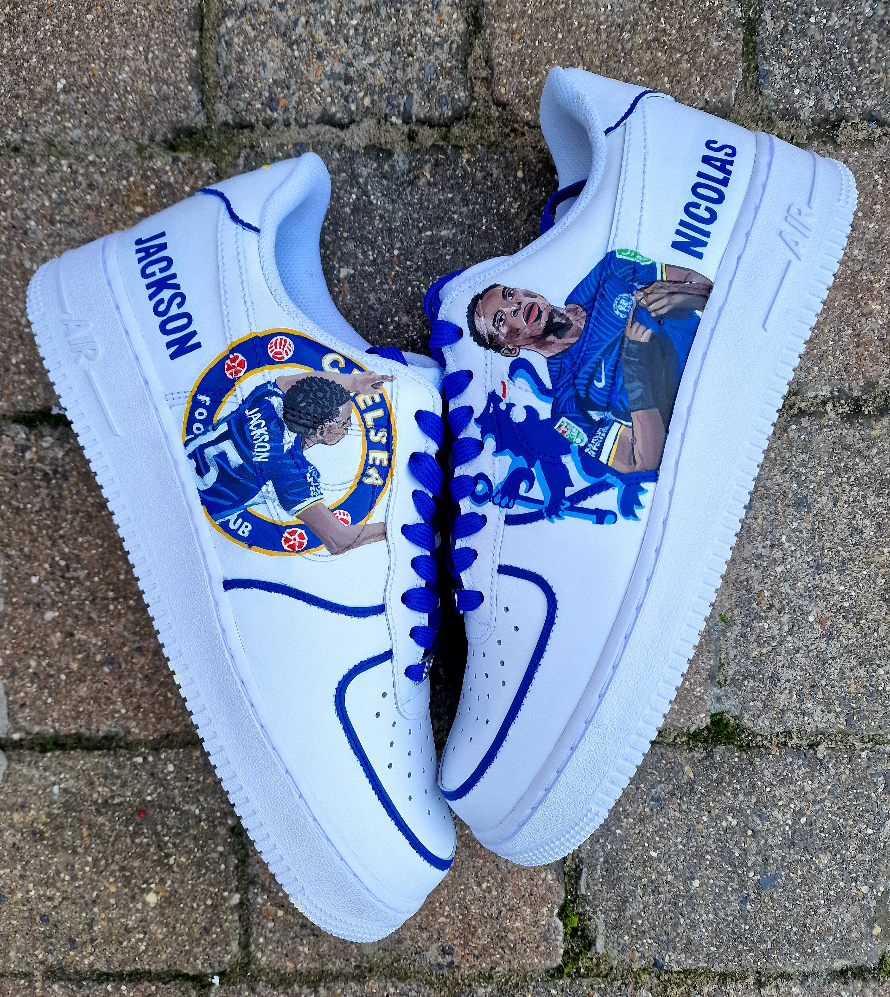 Custom hand-painted white sneakers featuring Chelsea FC’s Nicolas Jackson in vivid blue match kit, complete with the club badge and Senegal flag-inspired Nike swoosh. Designed by Gitartsy, the artwork includes realistic player portraits, fine detailing, and premium waterproof paint, making these shoes a perfect blend of fashion and football art.

