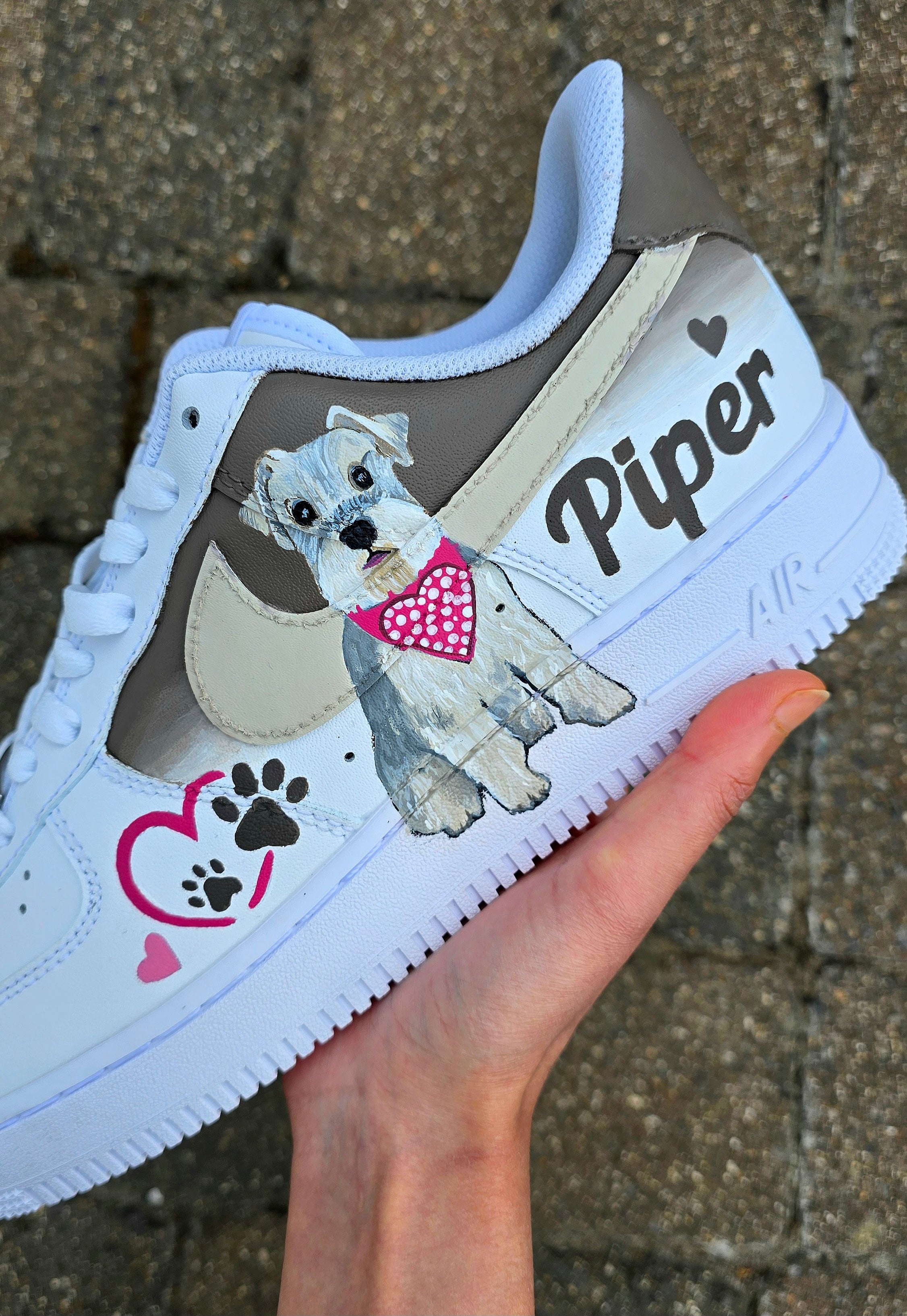 Hand-painted Nike Air Force 1 custom sneakers featuring a realistic pet portrait of “Piper” the dog 🐾, pink or taupe background, heart ❤️ and paw print accents, and personalised name detail, created by Gitartsy.

